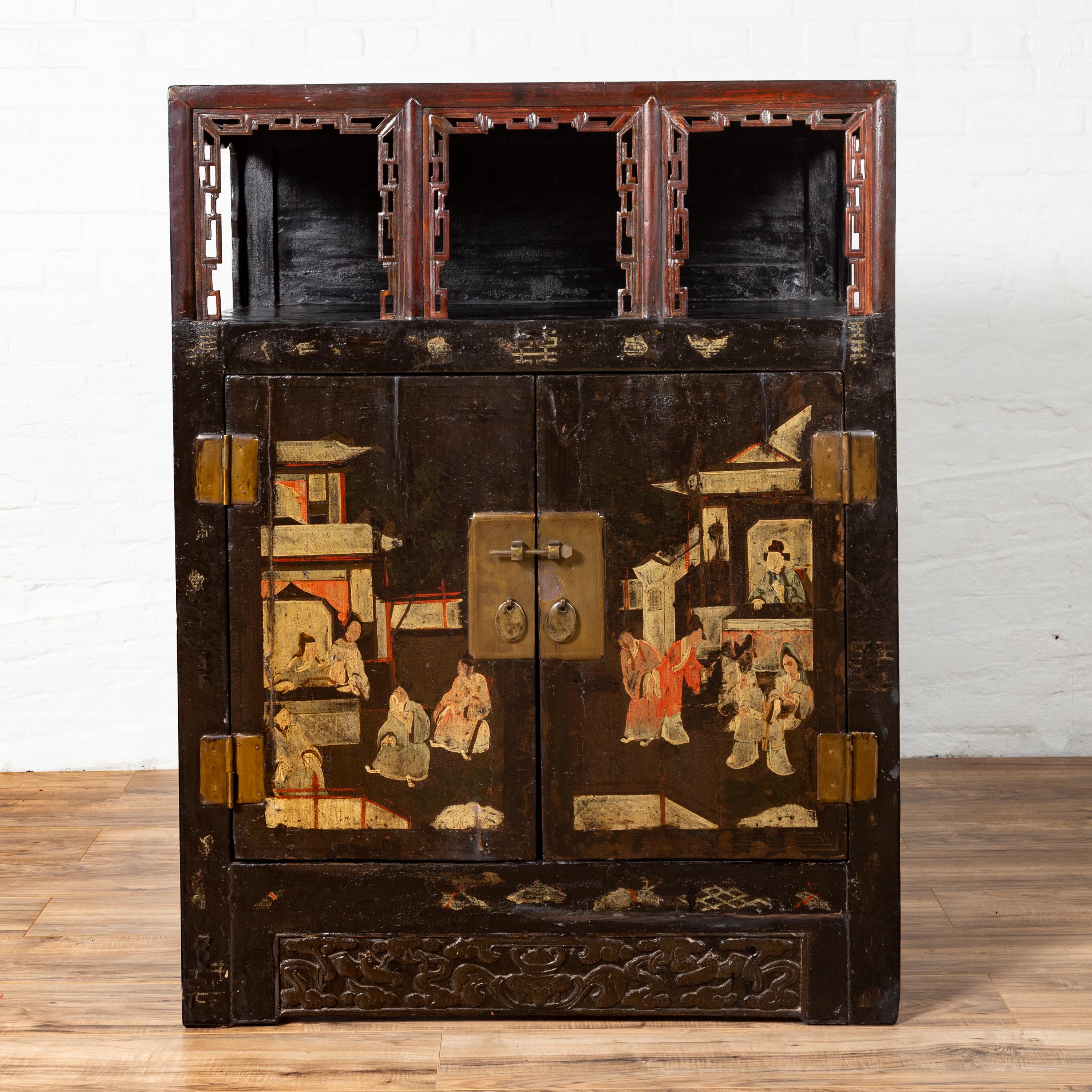 Chinese 19th century antique display cabinet with hand painted chinoiserie scene, open shelf, two doors and carved accents. Born in China in the 19th century, this exquisite display cabinet features an open shelf in its upper section, accented with