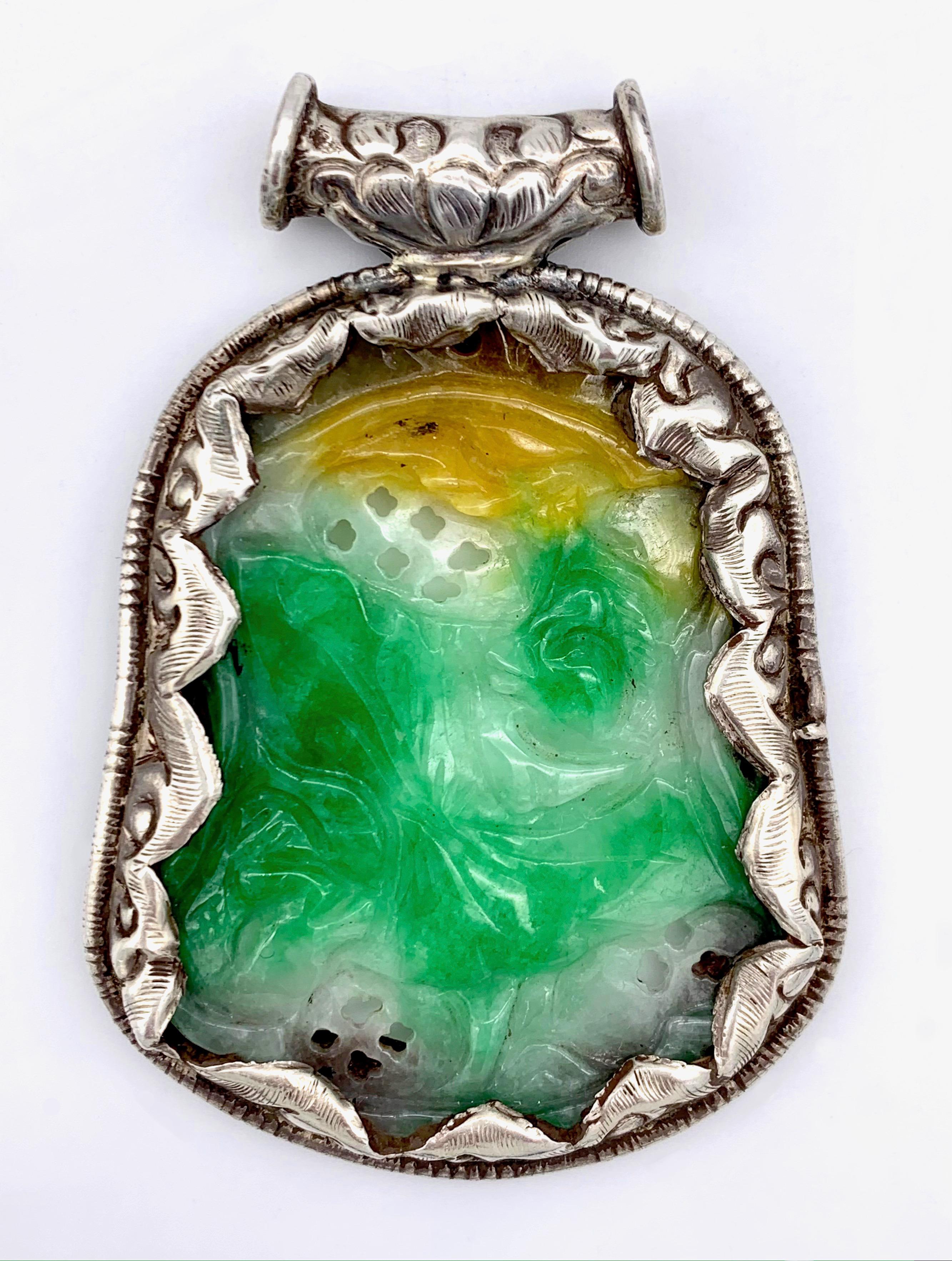 Cette magnifique pièce de jade sculpté est sertie dans une monture en argent très élaborée. Le jade est sculpté sur les deux faces.
Ce bijou a été exécuté vers 1880.  