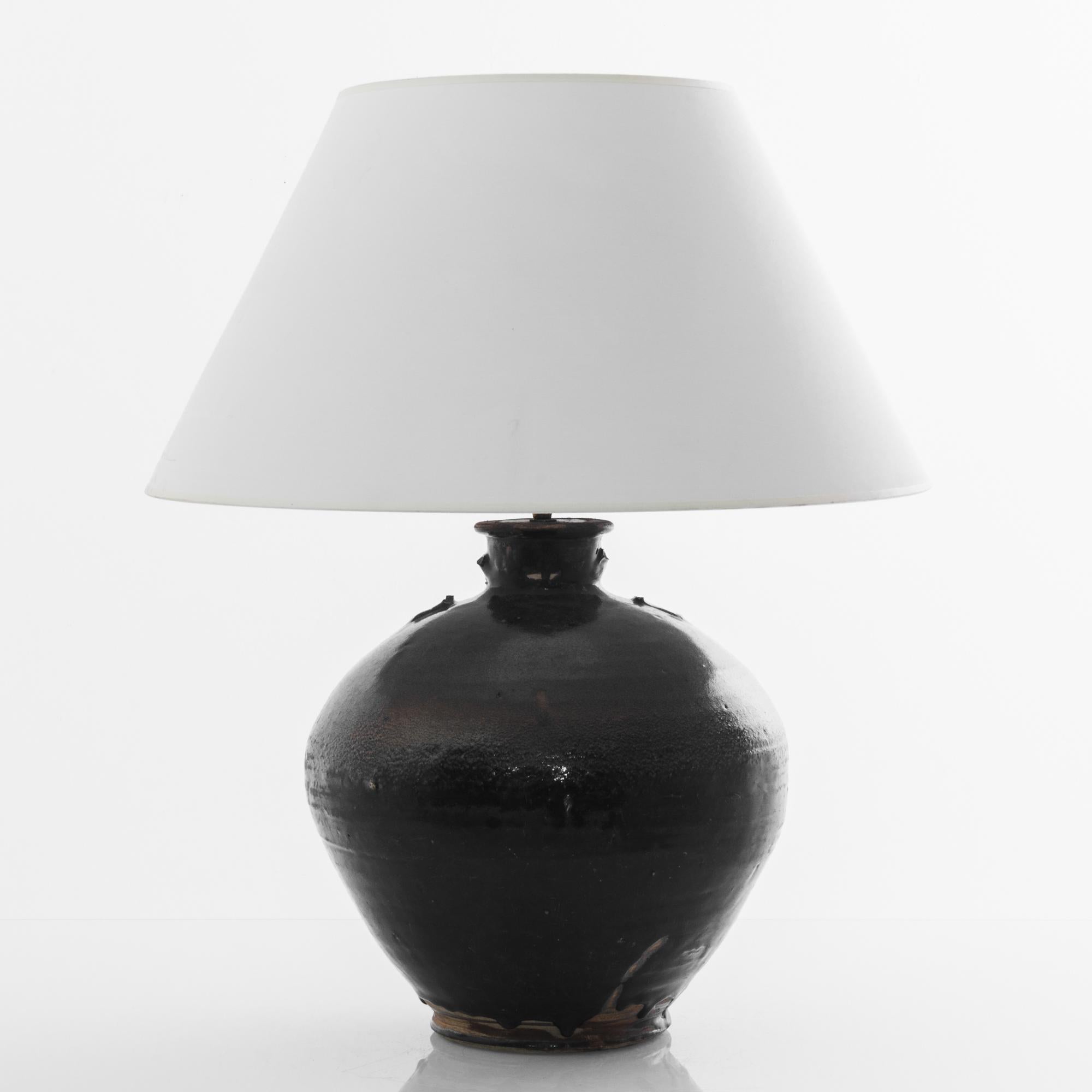 A vintage Chinese vase, fitted with an adjustable brass fixture and E26 lighting socket. The deep tone of the earthy black glaze creates a vivid visual impact. Textured glazes, attractive colors and curving shape grants a sensuous tactility to the