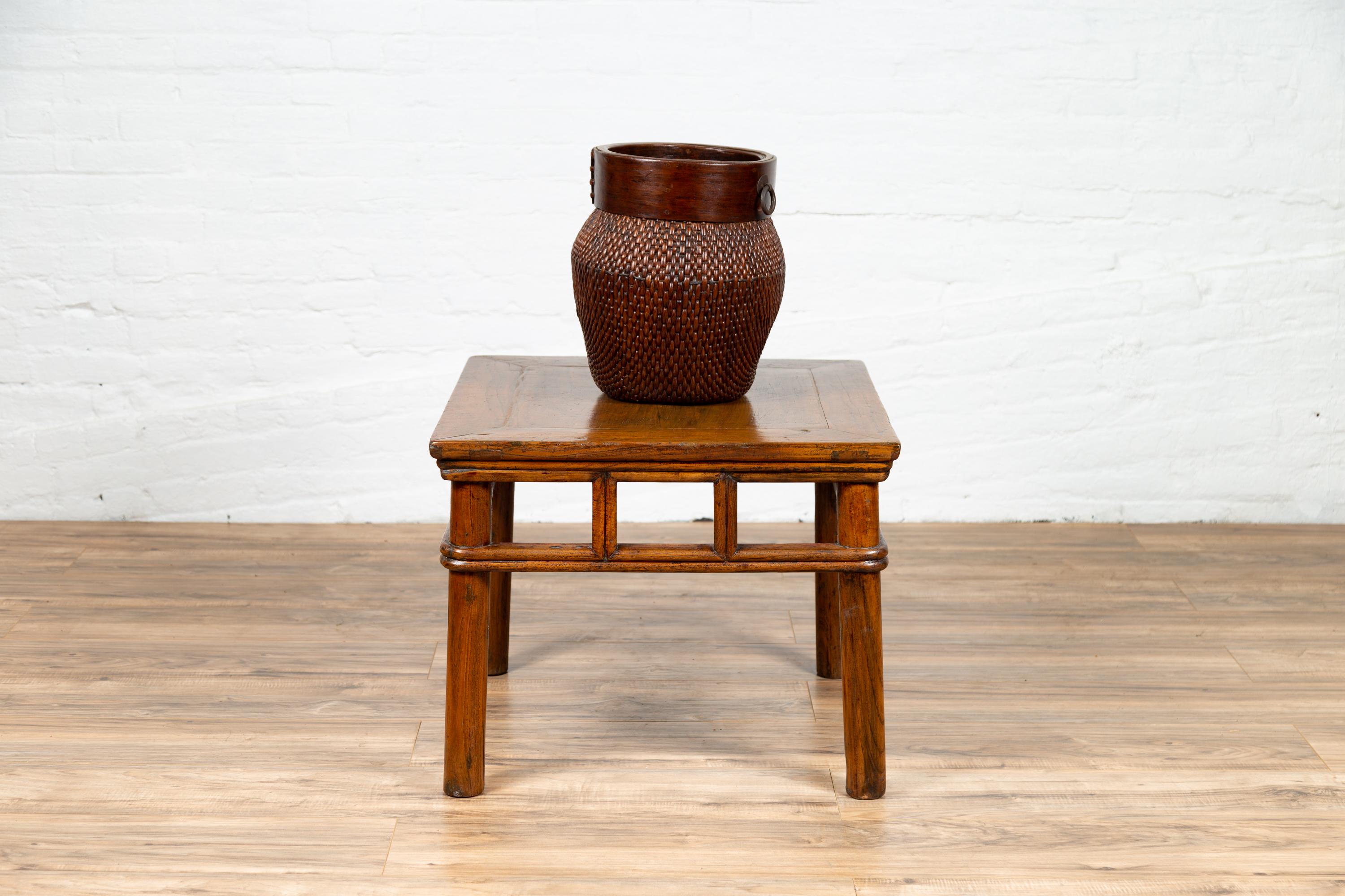 A Chinese Qing dynasty style elmwood side table from the early 20th century, with pierced pillar-shaped struts apron and cylindrical legs. This elegant Chinese side table features a rectangular top with central board and beveled edges, sitting above