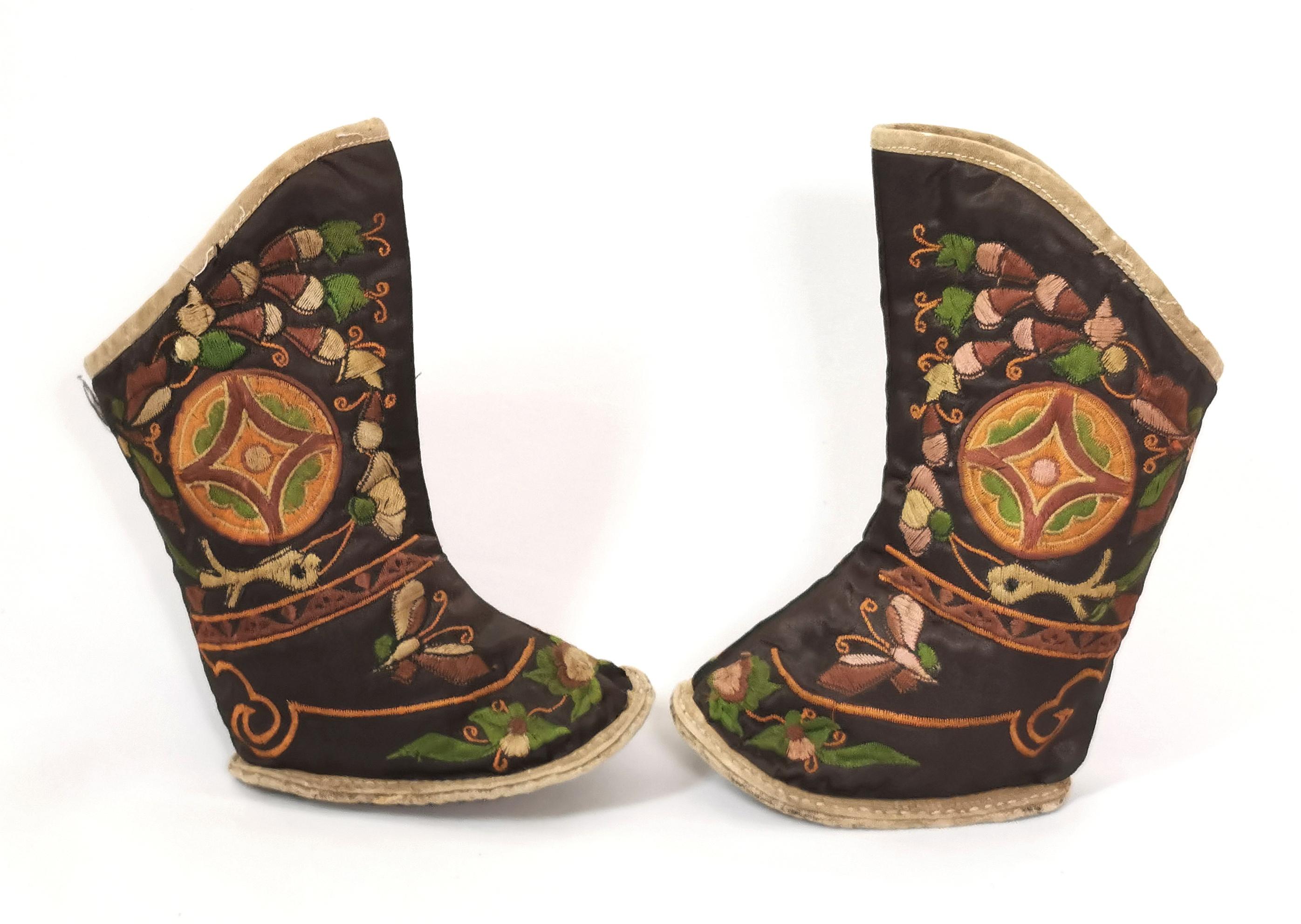 Une belle paire de bottes anciennes en soie brodée chinoise.

Ils sont parfaitement conçus avec des feuillages et des papillons brodés à la main sur un fond de soie brun chocolat.

Elles ont des semelles en tissu renforcé et sont légèrement plus
