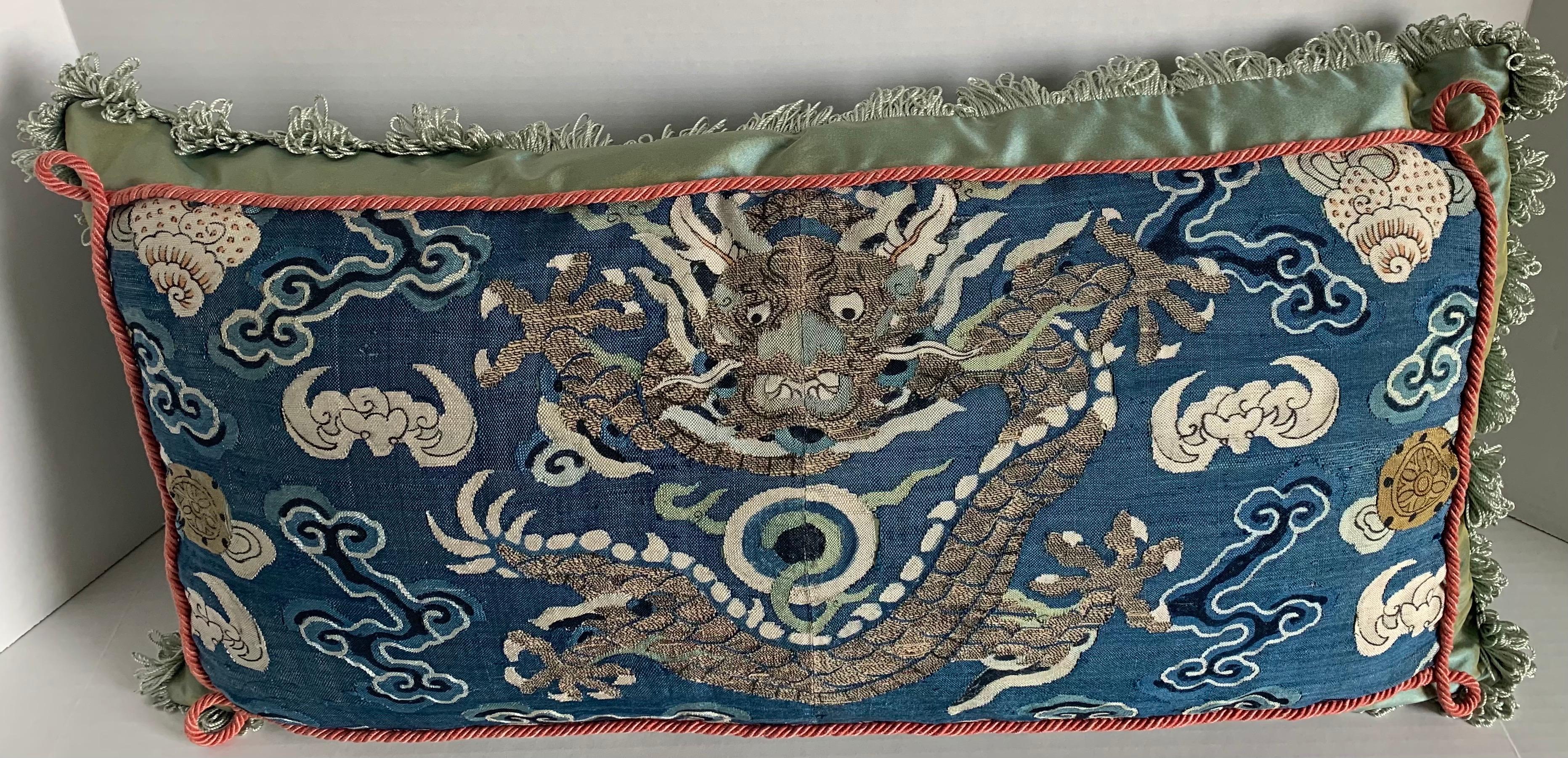 Antiker chinesischer bestickter Stoff, der zu einem maßgeschneiderten Lendenkissen verarbeitet wurde. Antiker blauer gewebter Seidenstoff mit Drachenmotiv in der Mitte.
Das Kissen ist aus Scalamandre schillernder, zeladongrüner Seide mit gebürsteten