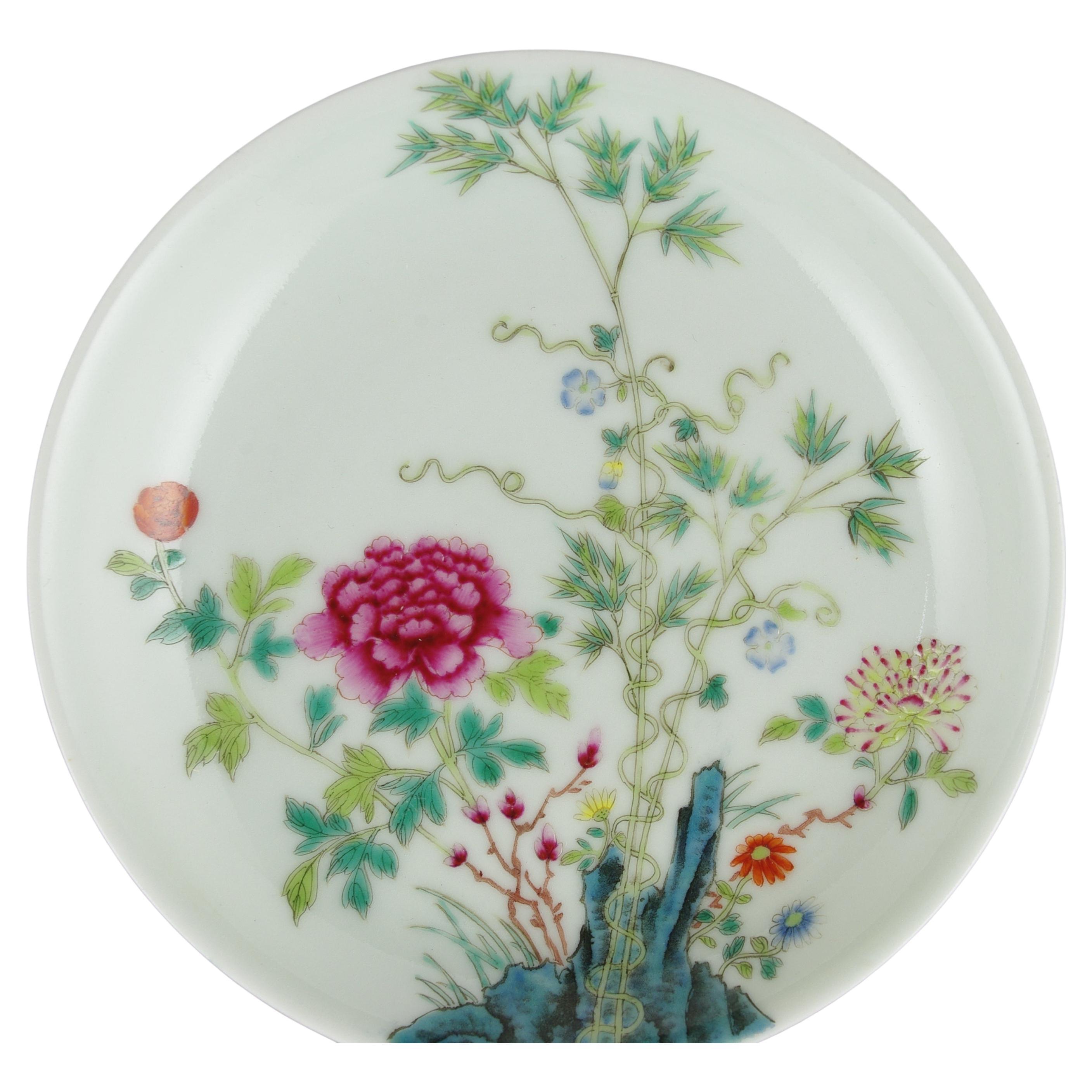 An antique Chinese famille rose fencai porcelain saucer dish, finely painted with a peony blossom in a rocky garden scene with bamboo and a scrolling vine, with six character vertical Guangxu mark to base within the footring in iron red

circa 1890,