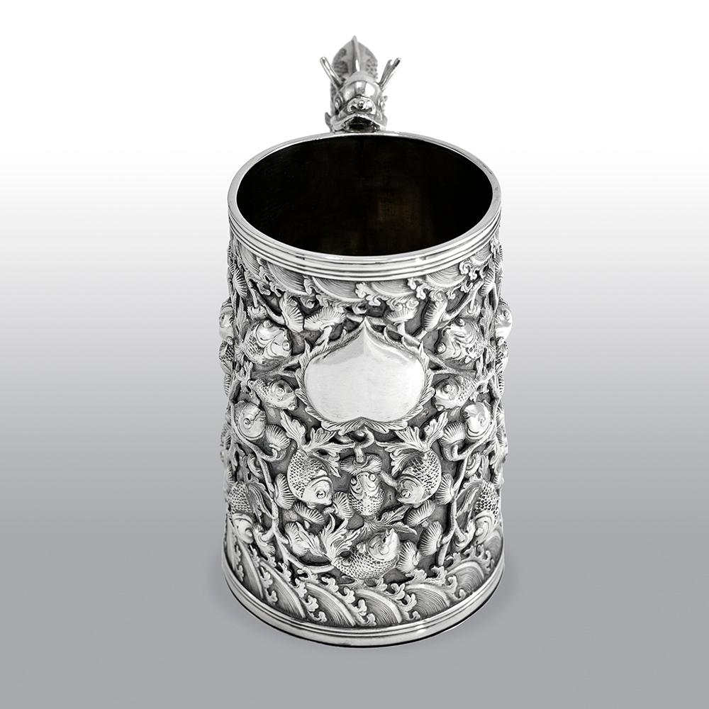 A fine and impressive antique Chinese Export large silver tankard, with pierced repousse decoration to the body depicting carp swimming amongst aquatic foliage and above a band of wave motifs, a tear-shaped cartouche to the centre, the decoration