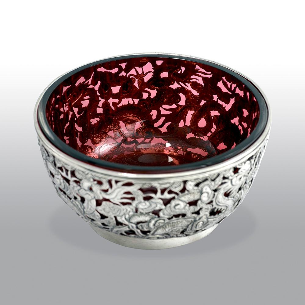This fine antique Chinese export bowl, pierced and chased with oriental dragons and cloud designs. The bowl is fitted with a cranberry glass liner and with hallmarks struck to the underside.

Retailed by Wang Hing 
Hong Kong
Silver mark