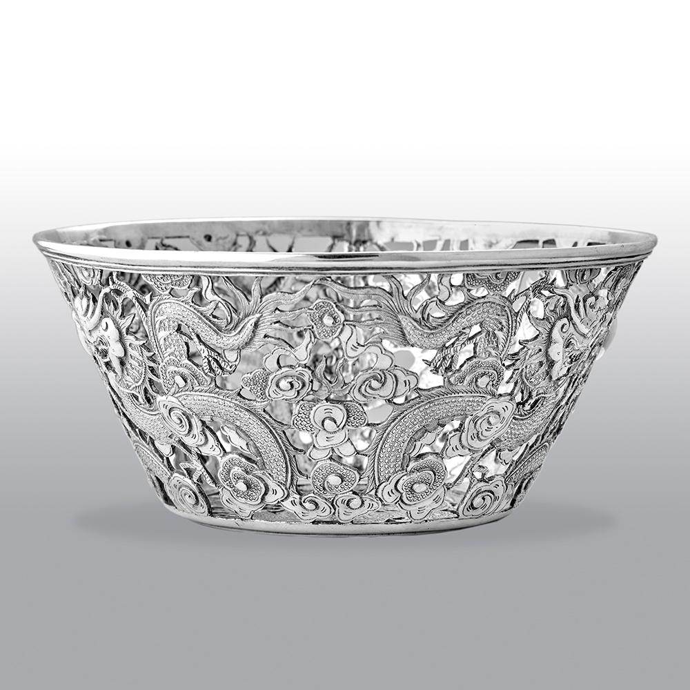 This fine antique Chinese export bowl, pierced and chased with oriental dragons and cloud designs and with hallmarks struck to the underside.

Maker: Wang Hing
Hong Kong
Silver mark 90

Weight: 146.9g.