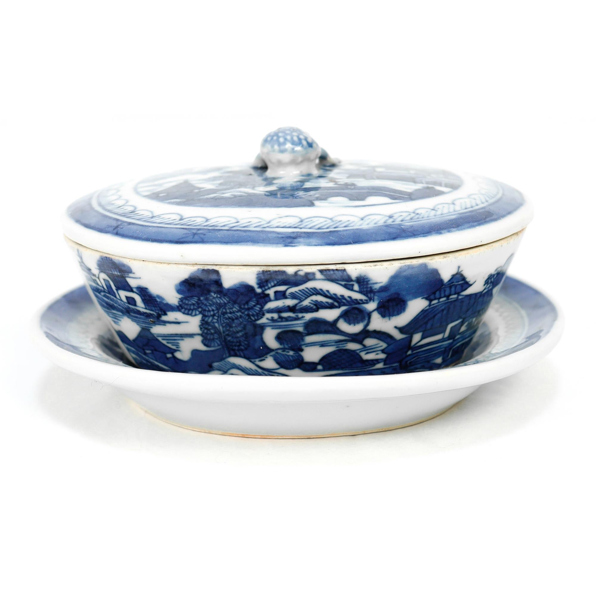 Un beurrier et un sous-plat couverts en porcelaine d'exportation chinoise.

Dans le modèle de Canton.

Décor en bleu sous glaçure d'un village chinois montagneux avec des maisons, des montagnes, des feuillages, une rivière et un bateau. 

Le