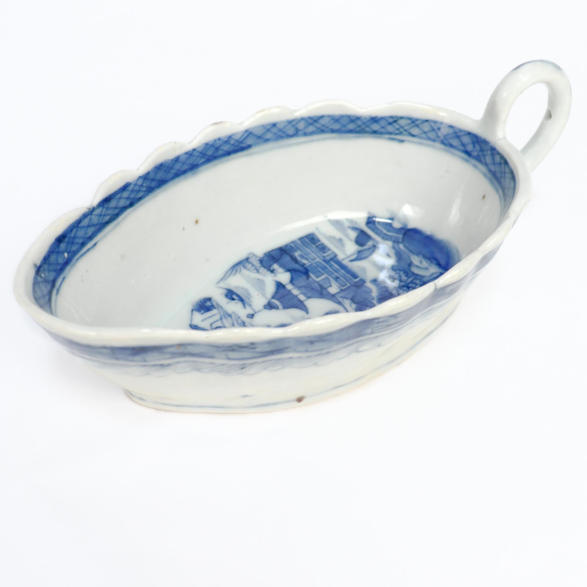 A fine antique Chinese Export porcelain gravy boat or sauce boat.

In the Canton pattern.

Decorated in underglaze blue with a mountainous Chinese village with houses, mountains, foliage, and a river and boat.

With an applied handle and scalloped