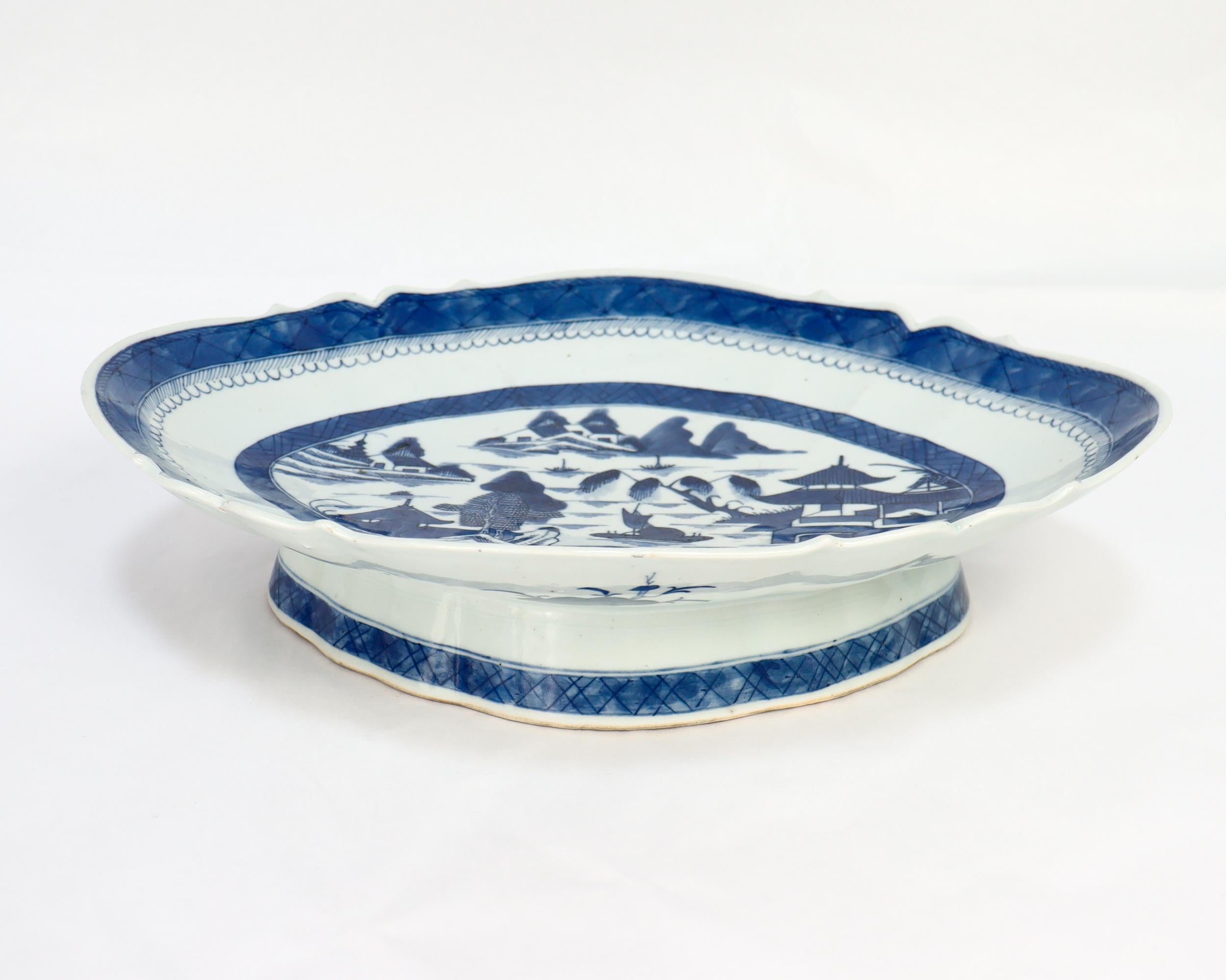 Rare plateau à pied ou compotier en porcelaine d'exportation chinoise ancienne.

Dans le modèle de Canton.

Décor en bleu sous glaçure d'un village chinois montagneux avec des maisons, des montagnes, des feuillages, une rivière et un bateau. 

Avec
