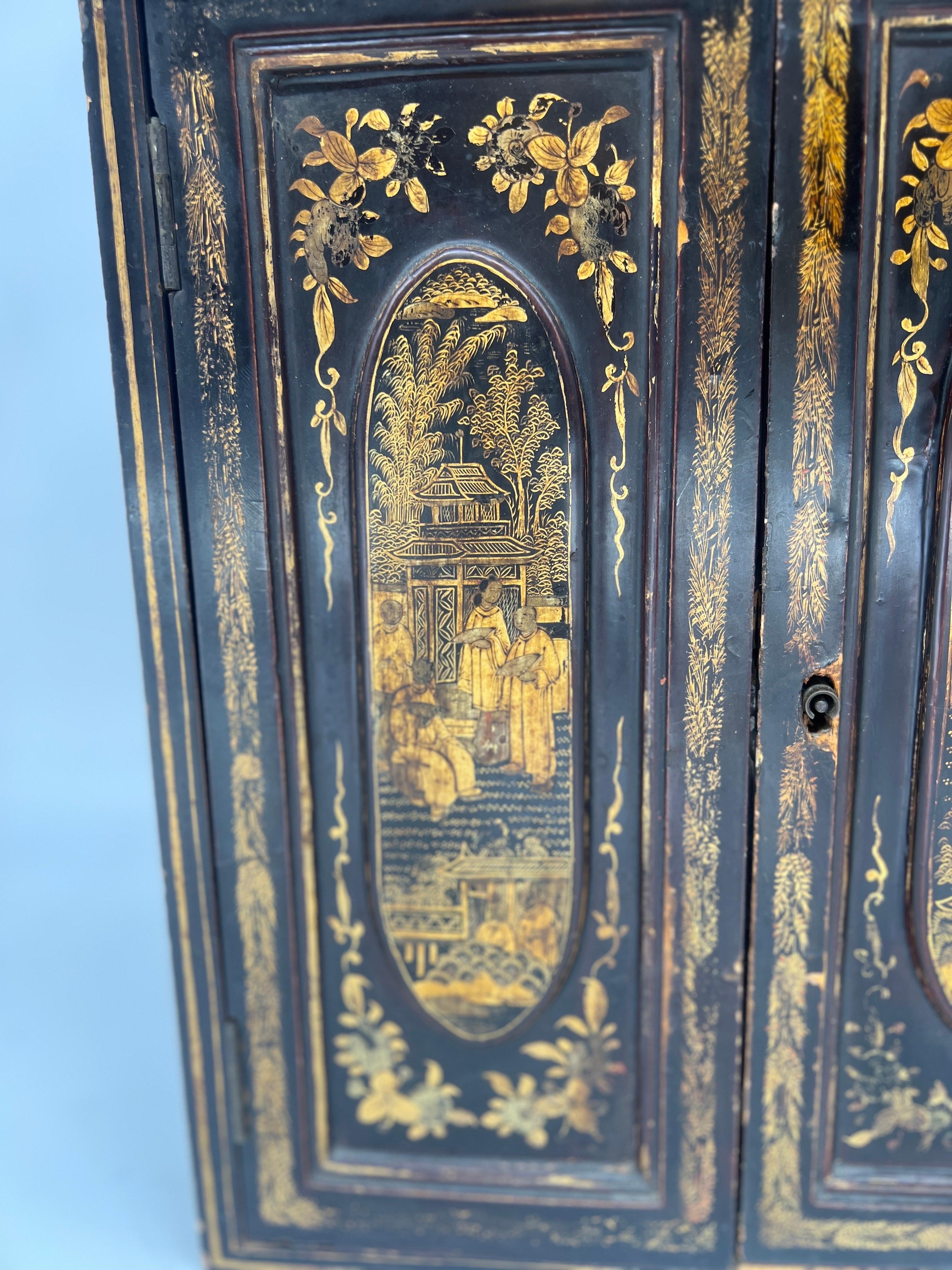 Chinese export, 19th century. This finely lacquer and gilt decorated cabinet features traditional Chinese figures decorated to the body of the two door cabinet. When opened they reveal a 5 drawer interior with round carved bone 