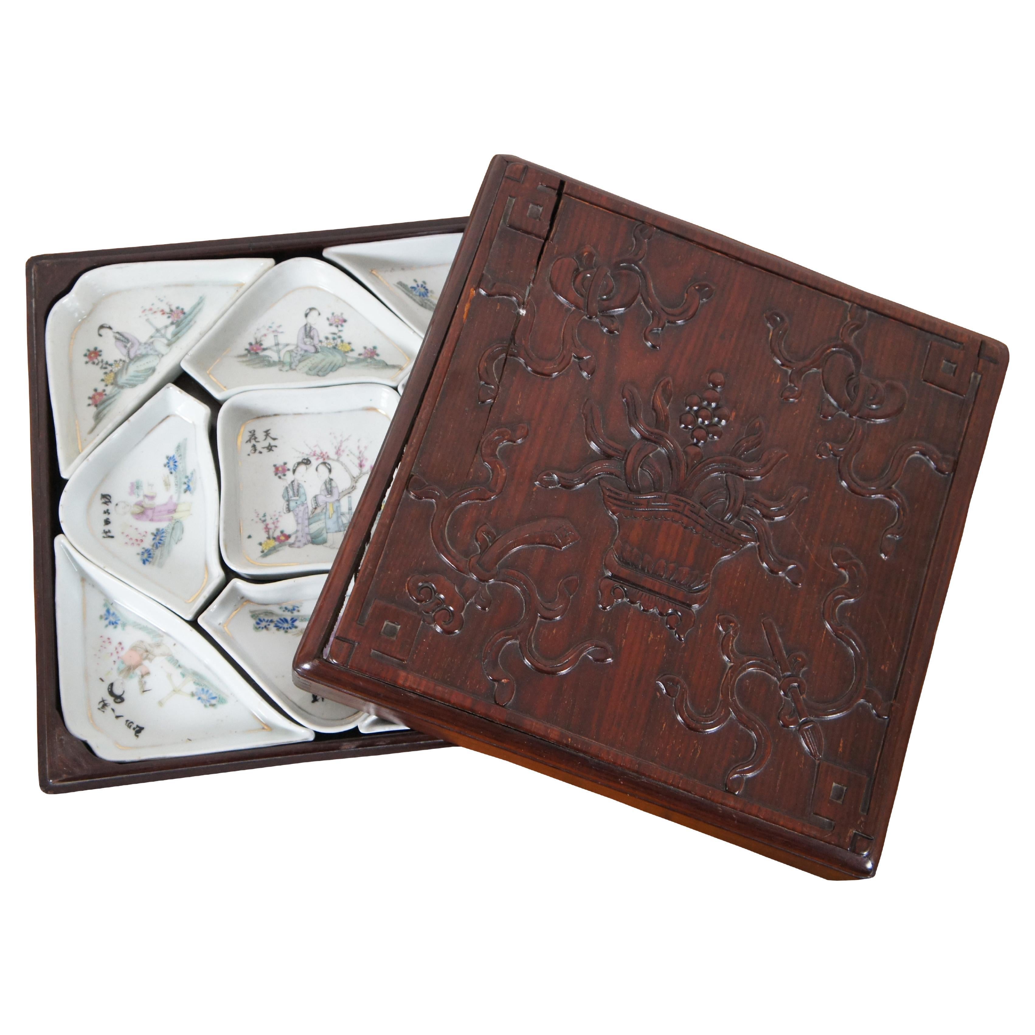 Antique 19th century Chinese Export, famille rose porcelain sweet meat / hors d’oeuvre dishes in a Rosewood box elegantly carved with ribbons and a basket of flowers. Features 9 dishes arranged geometrically with scenes of Geishas and Scholars.