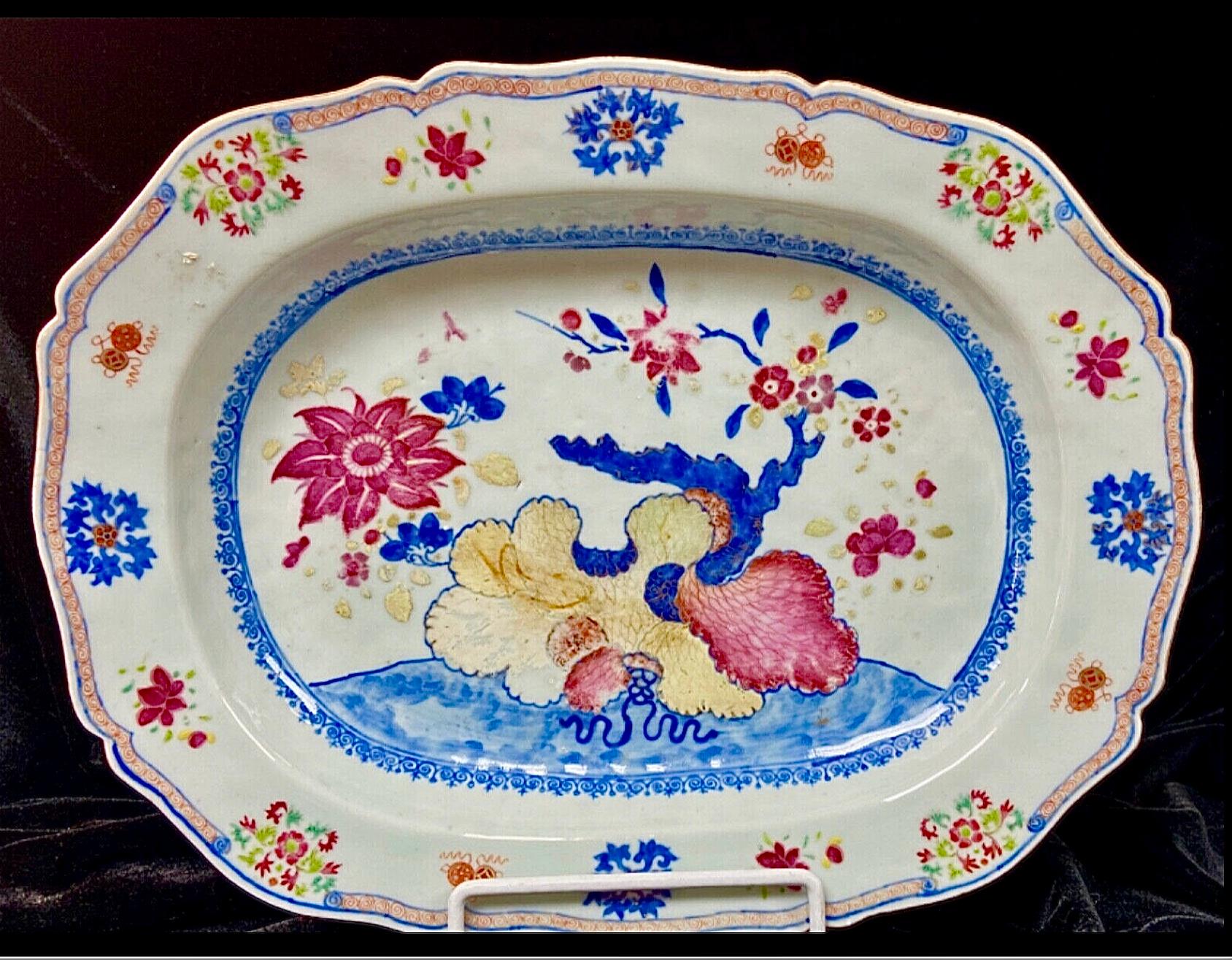 A large Chinese Export Famille Rose charger with pink lotus and other flowers. Painted in bright vivid colors of blues, reds and yellow accents.