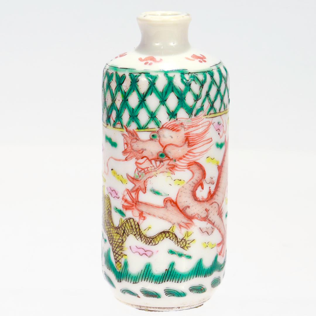 A fine antique Chinese Export porcelain snuff bottle (or small cabinet vase).

With painted decoration to the body of two dragons and a flaming pearl, small clouds in green, yellow, and pink, and red & green geometric devices.

There are two small