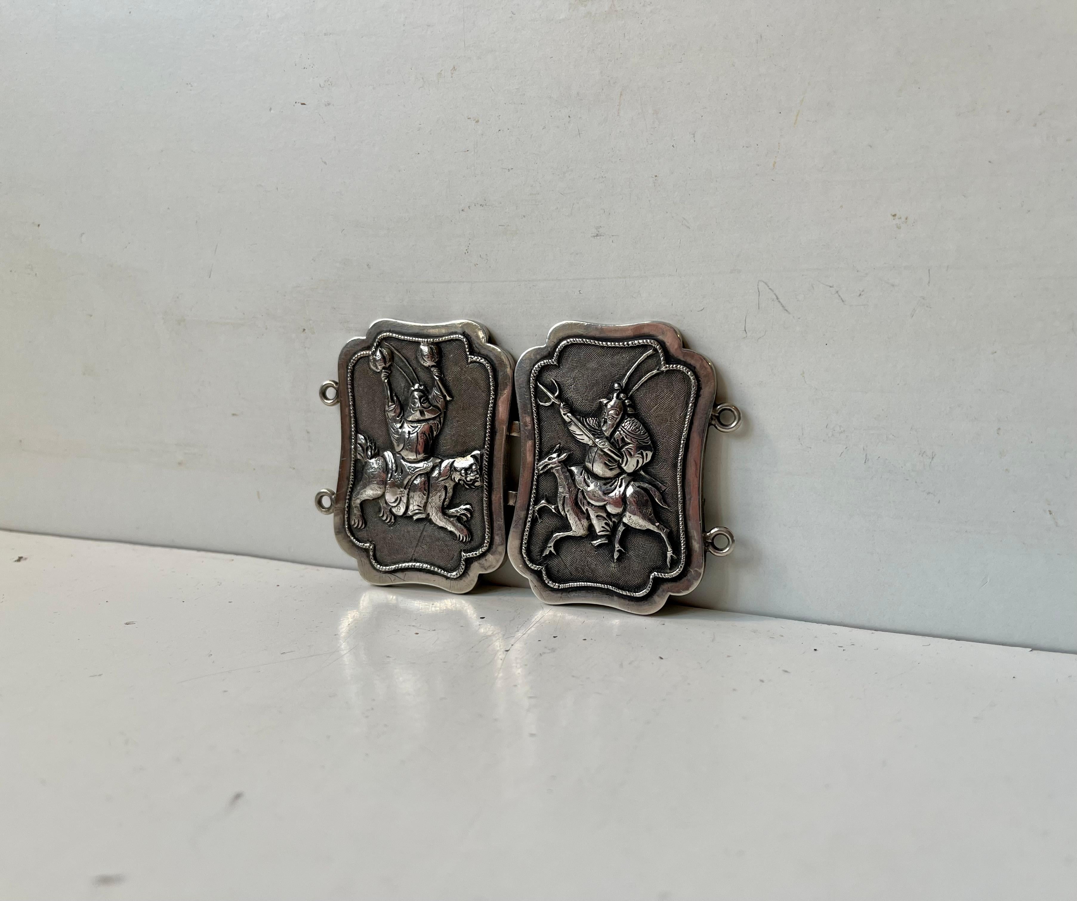 Two-piece belt buckle in sterling silver. Made in Woshing Shanghai circa 1910. It depicts samurais riding on Foo Dogs/Lions on a matte textured background. Very fine details and clear hallmarks to its backside. WS for Woshing - Shanghai and Chinese