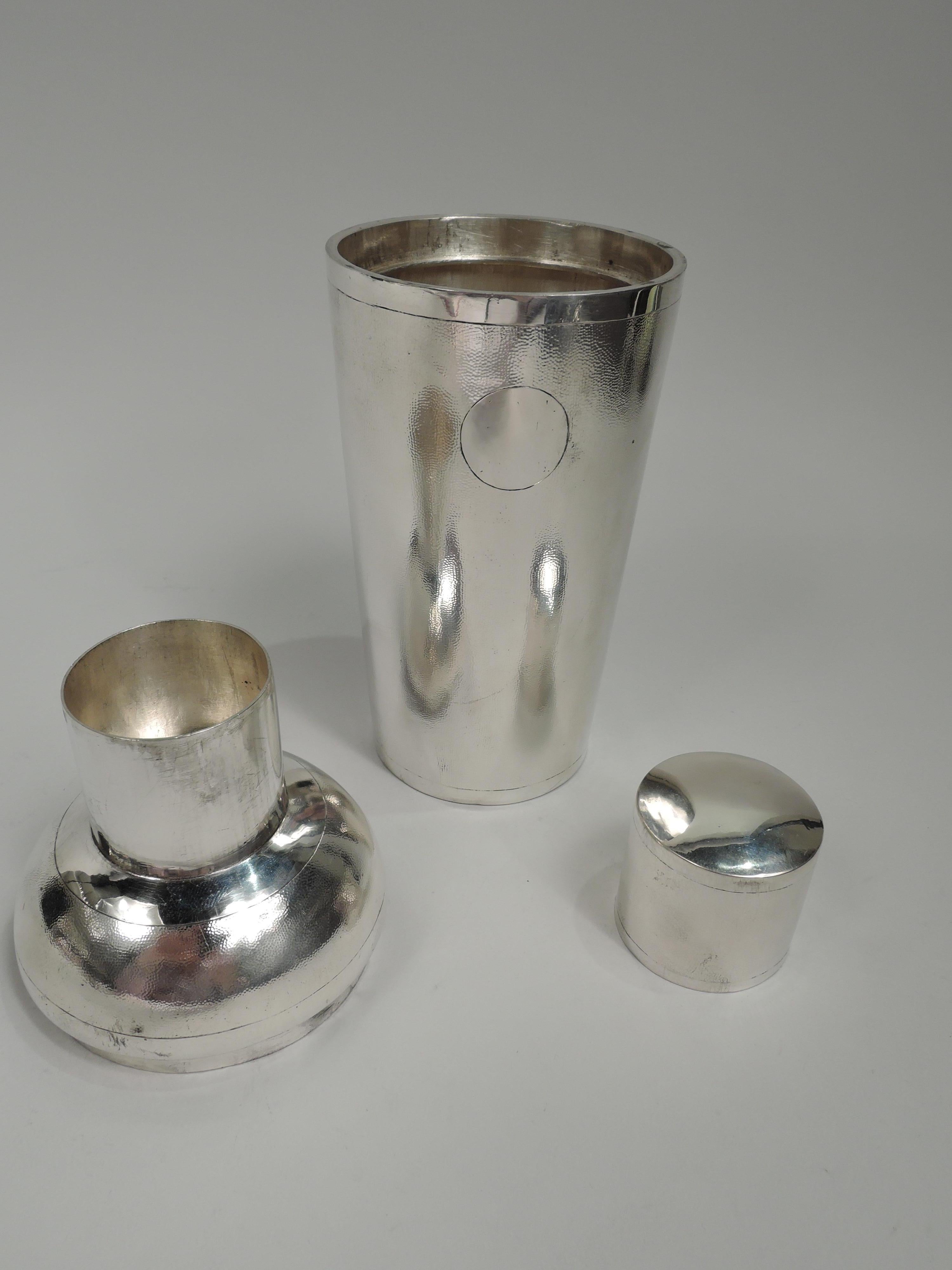 Chinese export silver cocktail shaker, ca 1910. Straight and tapering bowl. Detachable top with curved shoulder and straight and inset cylindrical neck with built-in strainer and snug-fitting cap. Allover stippling and plain bands, circle (vacant),