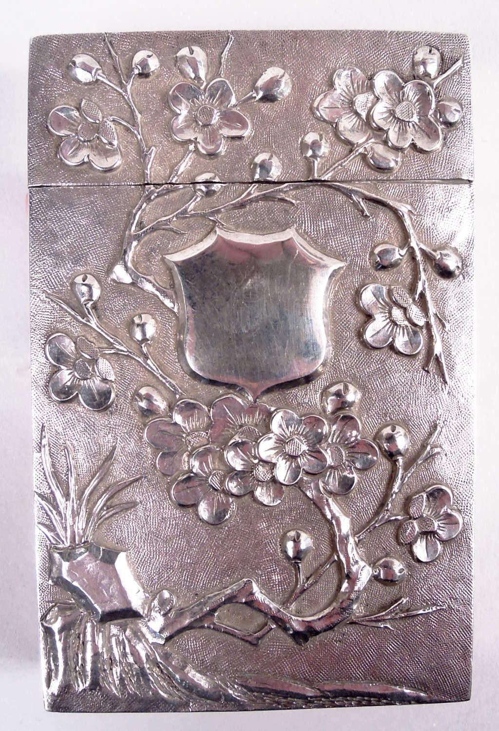 Portacarte cinese in argento da esportazione, 1910 circa. Rettangolare. Ornamenti cesellati su fondo punteggiato. Al recto, un ramo di pruno in fiore con cartiglio armoriale (vacante). Sul verso, un drago con zanne e artigli. Il coperchio si adatta