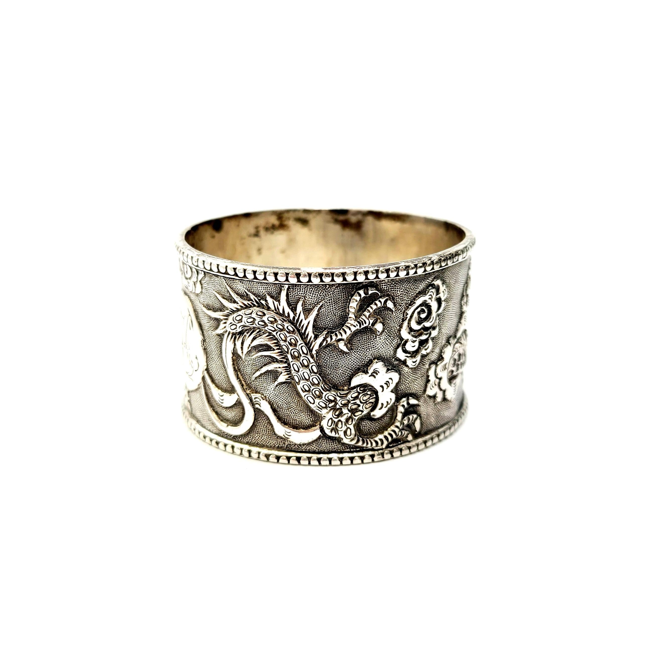 Antique Chinese export silver napkin ring.

Beautifully ornate napkin ring features intricate Chinese dragons on a textured background. Round cartouche with monogram.

Monogram appears to be AH.

Measures approx 1 1/8