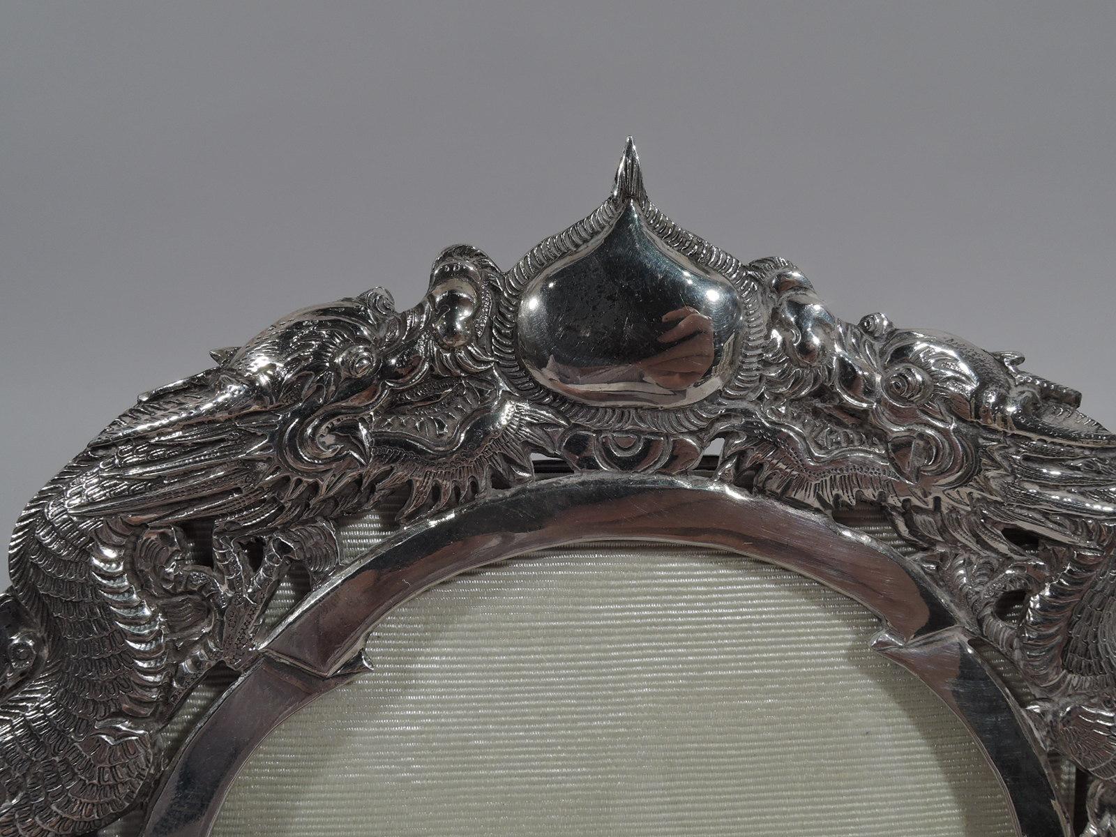 Turn-of-the-century Chinese export silver frame. Oval window in chased and embossed horseshoe surround: A scaly, serpentine dragon on each side and winged horses at bottom. A dramatic showcase for a formidable matriarch. Marked. 

Dimensions: