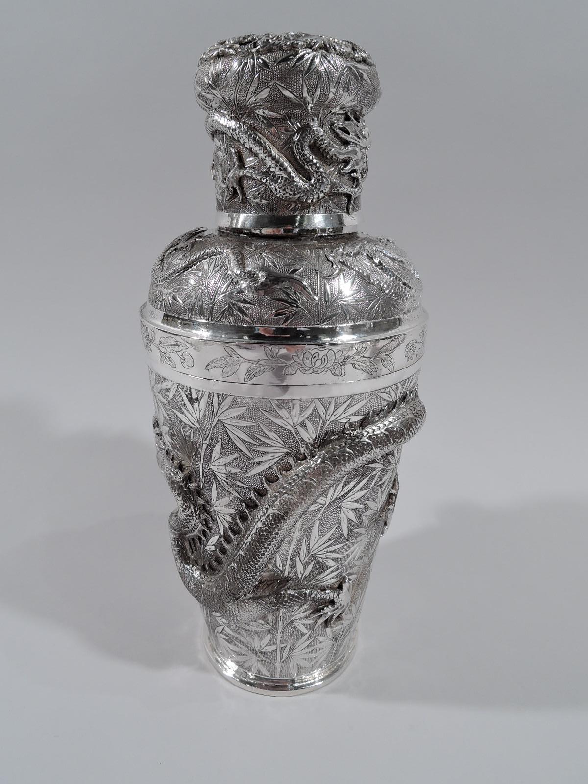 Chinese silver firewater cocktail shaker, circa 1910. Tapering cup. Detachable top has curved shoulder with built-in strainer and straight neck; bellied cover. Bamboo-patterned ground with applied dragons—ferocious, scaly beasts with major