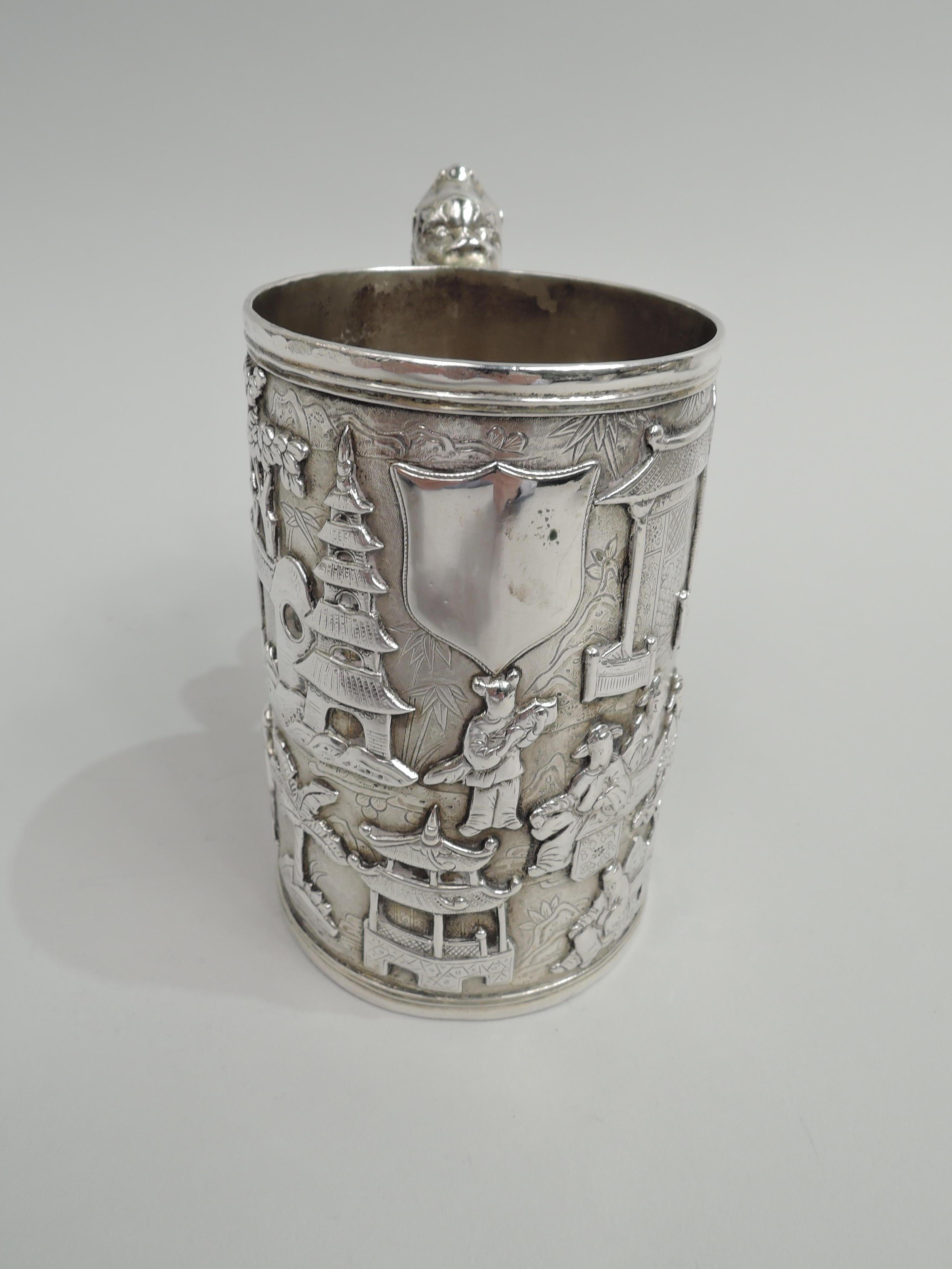 Chinese export silver mug, ca 1860. Straight and upward tapering sides with applied pictorial frieze on engraved and stippled ground: Scenes of social life with contemplative sages and chaste maidens amongst palm trees and pagodas. Pastoral