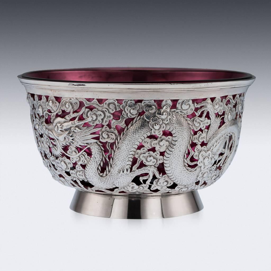 Antique 19th century Chinese Export solid silver bowl, the sides are profusely chased and pierced, depicting dragons chasing the flaming pearl of wisdom among clouds, good size and stunning workmanship, fitted with a translucent red liner.

The