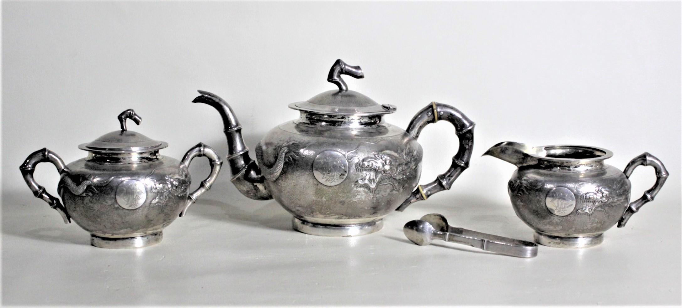 This antique handcrafted sterling silver tea set was made in China in circa 1880 in the period Chinese export style. The set is composed of a teapot, creamer and lidded sugar bowl and a set of thongs. Each piece of the set has a very detailed chased