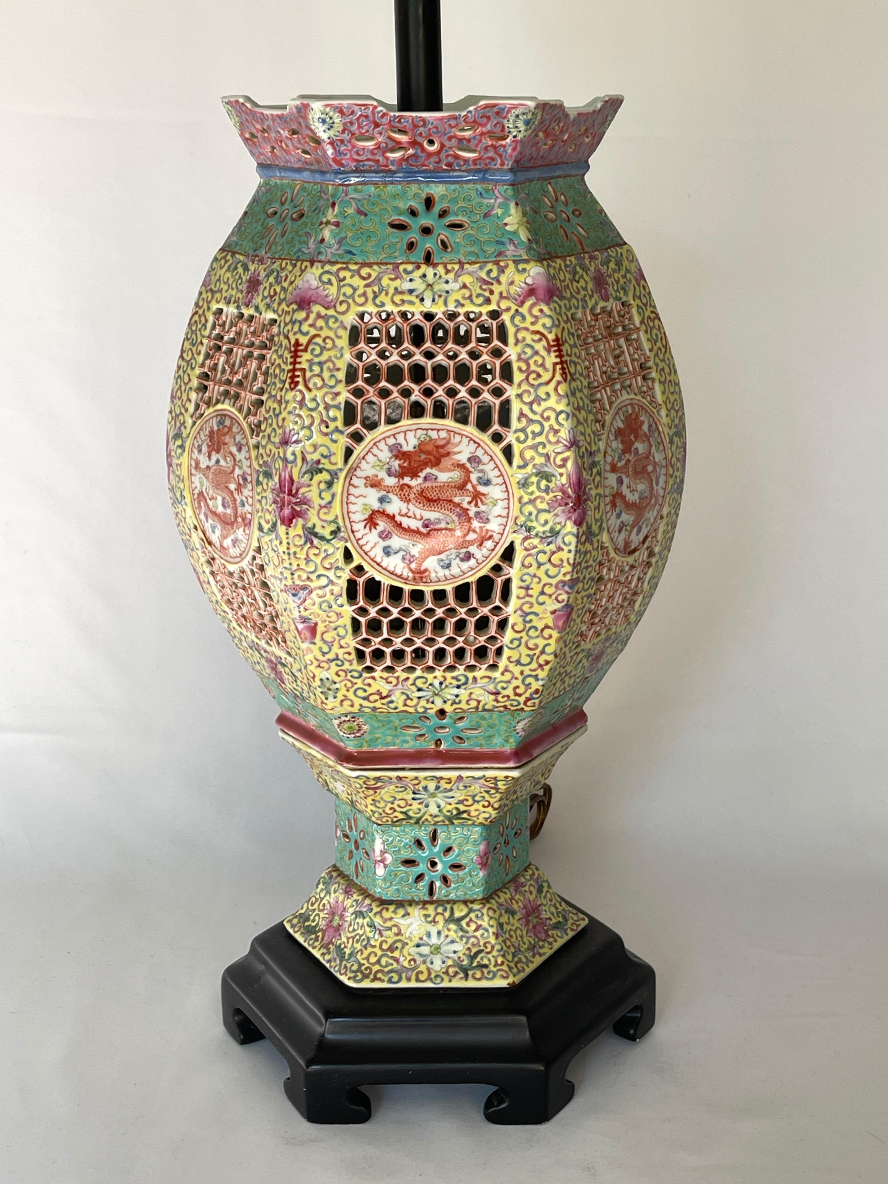 Late 19th- Early 20th century Chinese famille rose porcelain reticulated wedding lantern lamp with central Imperial Dragon motif medallions.
The lamp is composed of the porcelain lantern set on a dark hardwood hexagonal form base. Solid brass