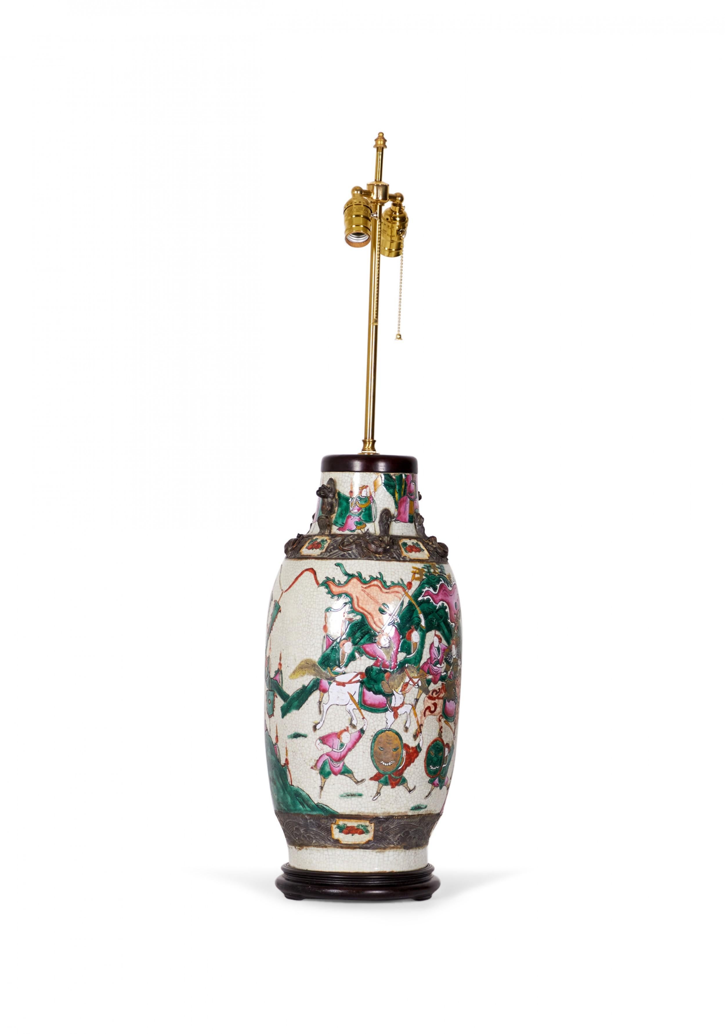 Lampe de table chinoise ancienne composée d'un vase en porcelaine du XVIIIe siècle monté avec du bois et des ferrures en laiton comme lampe, d'une famille rose multicolore et d'une scène de genre représentant une procession sur un fond beige. (Lampe