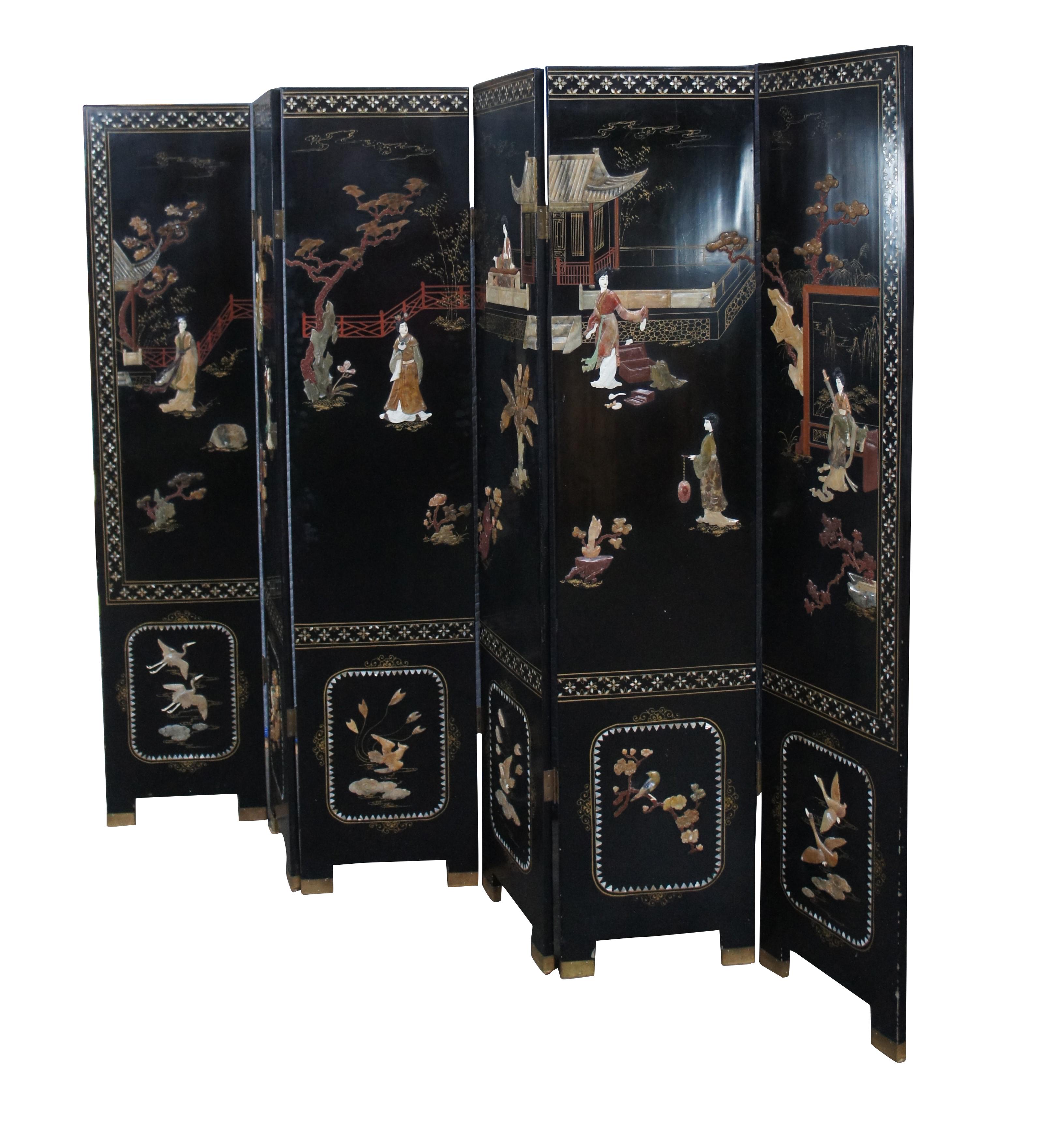 Exquis paravent à six panneaux de style Chinoiserie du milieu du 20e siècle.  Le cadre en laque noire est décoré d'une scène de jardin oriental traditionnel avec des figures en relief en pierre de savon et des incrustations de nacre. Il s'agit d'un