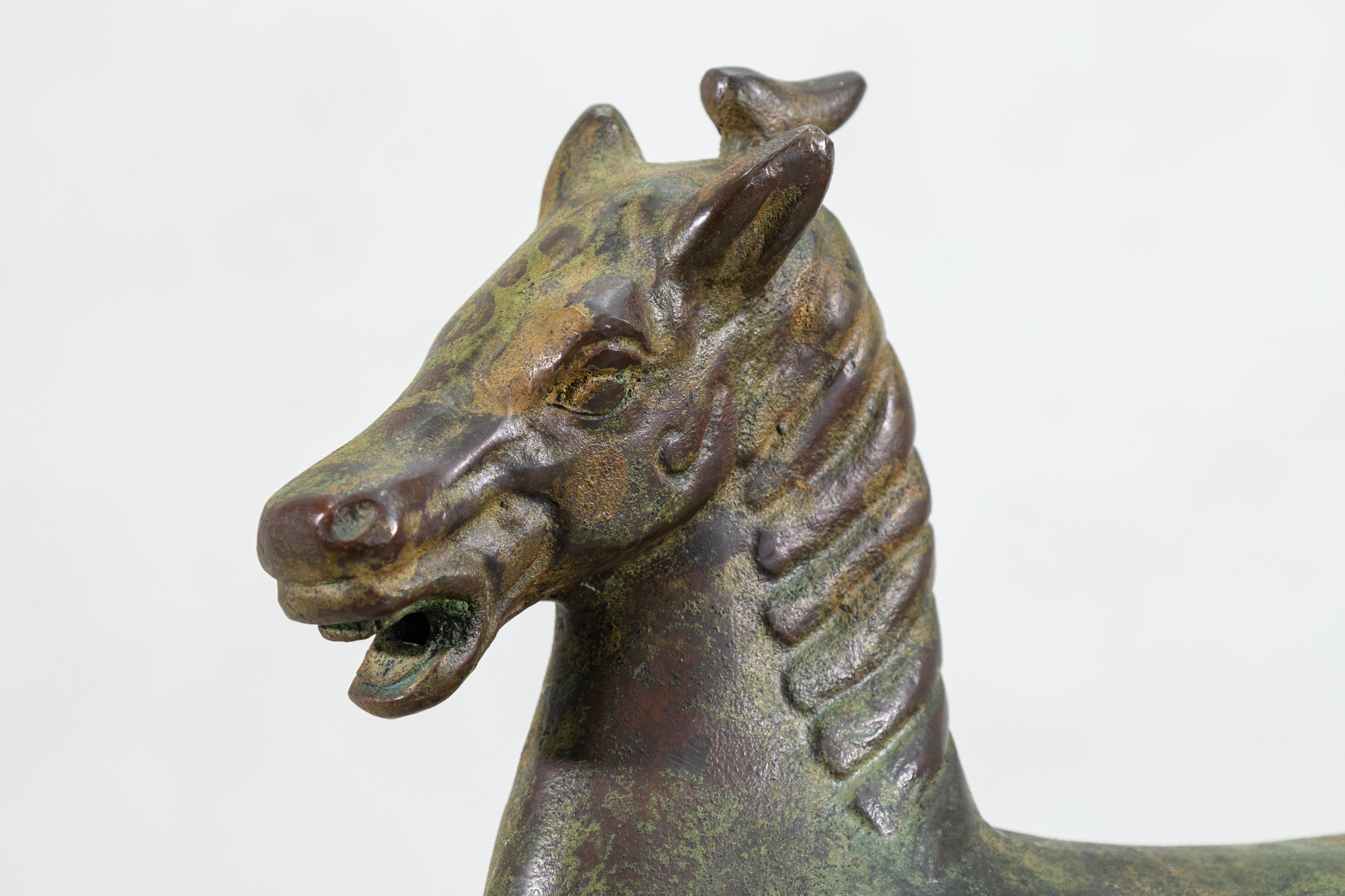 An antique Chinese patinated green cast bronze statue depicting a flying horse from the Gansu Province in western China. Circa early 20th century. A dynamic composition which captures the movement and motion of a galloping horse. This realistic