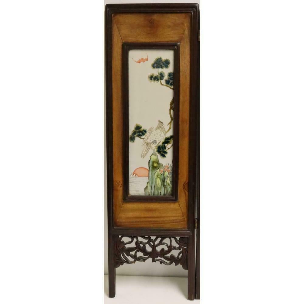 Three-panel folding screens with central porcelain plaque depicting a standing royal with attendants flanked by panels depicting foliage, birds, and bat. From a Southampton, Framed by hardwood with an intricated carving of curvilinear flowing