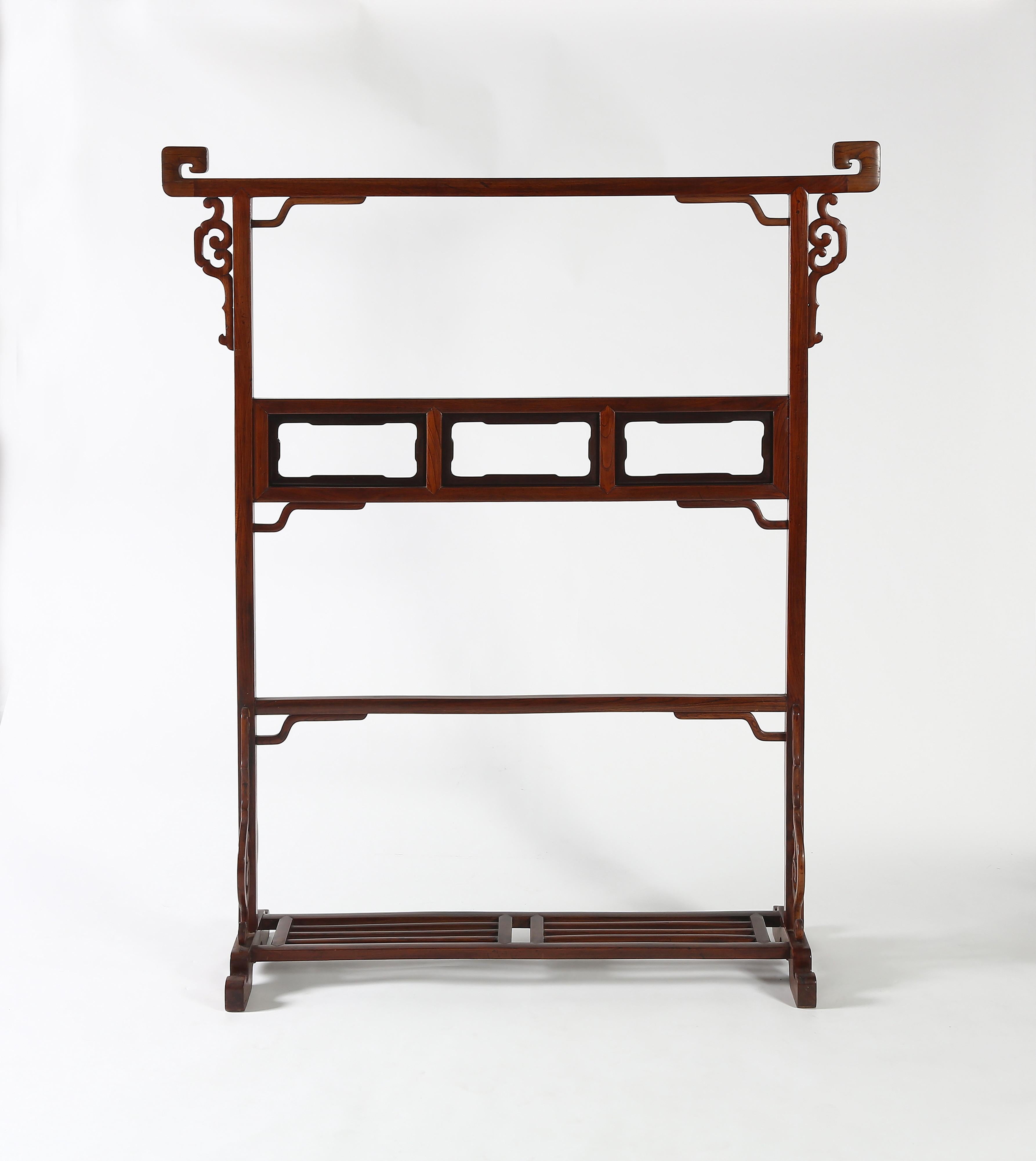 FINE CLOTHES RACK
The top rail with scroll ends to prevent the clothing from sliding off, supported on side posts decorated with open-carved spandrels, braced with a central panel decorated with open cartouches and a lower stretcher, decorated with