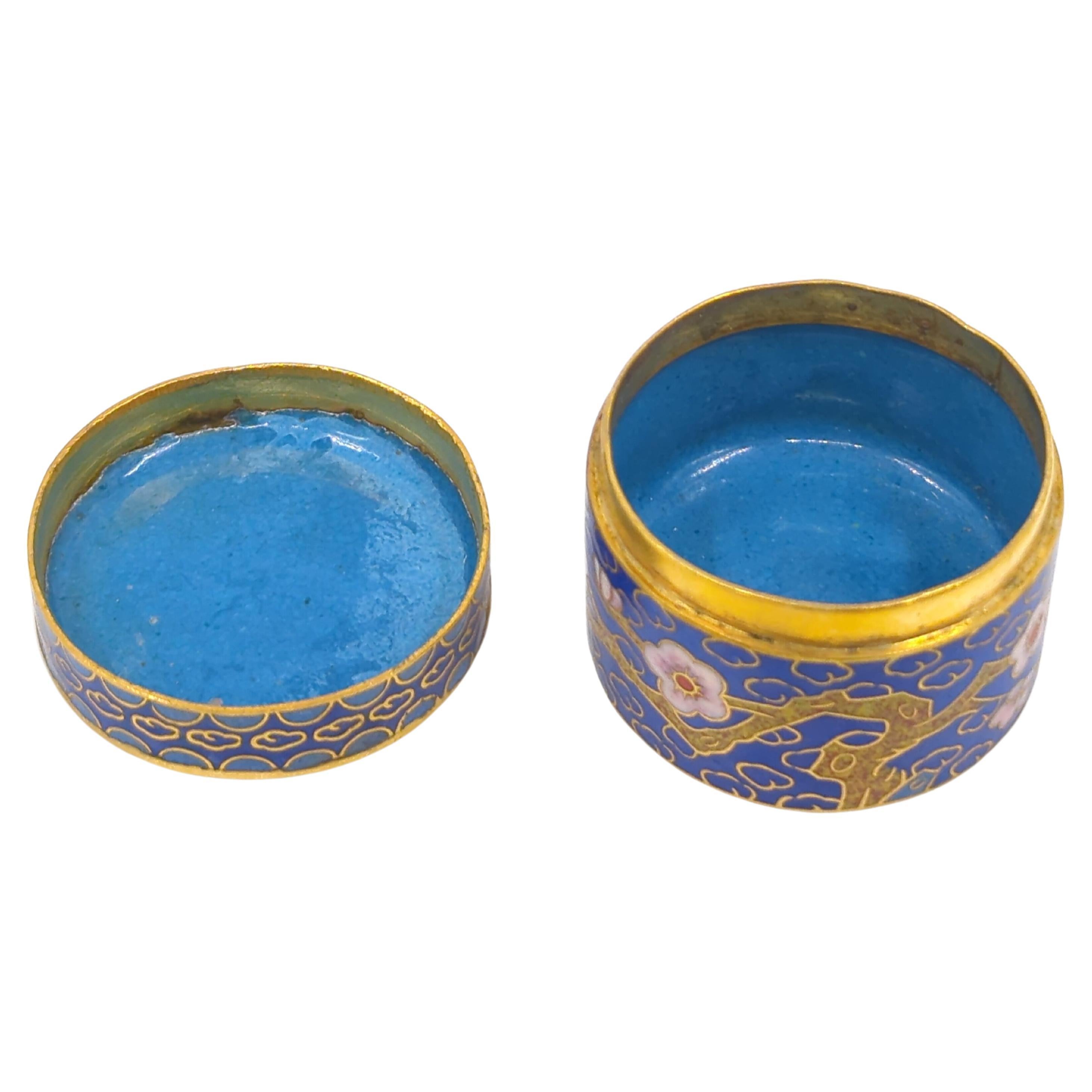 Antique Chinese cloisonne enamelled covered small round box, on sacrificial blue ground and finely decorated with colorful, lively prunus blossoms on branches, interior and bottom enamelled in powder blue and with gilt gold details

This wonderfully