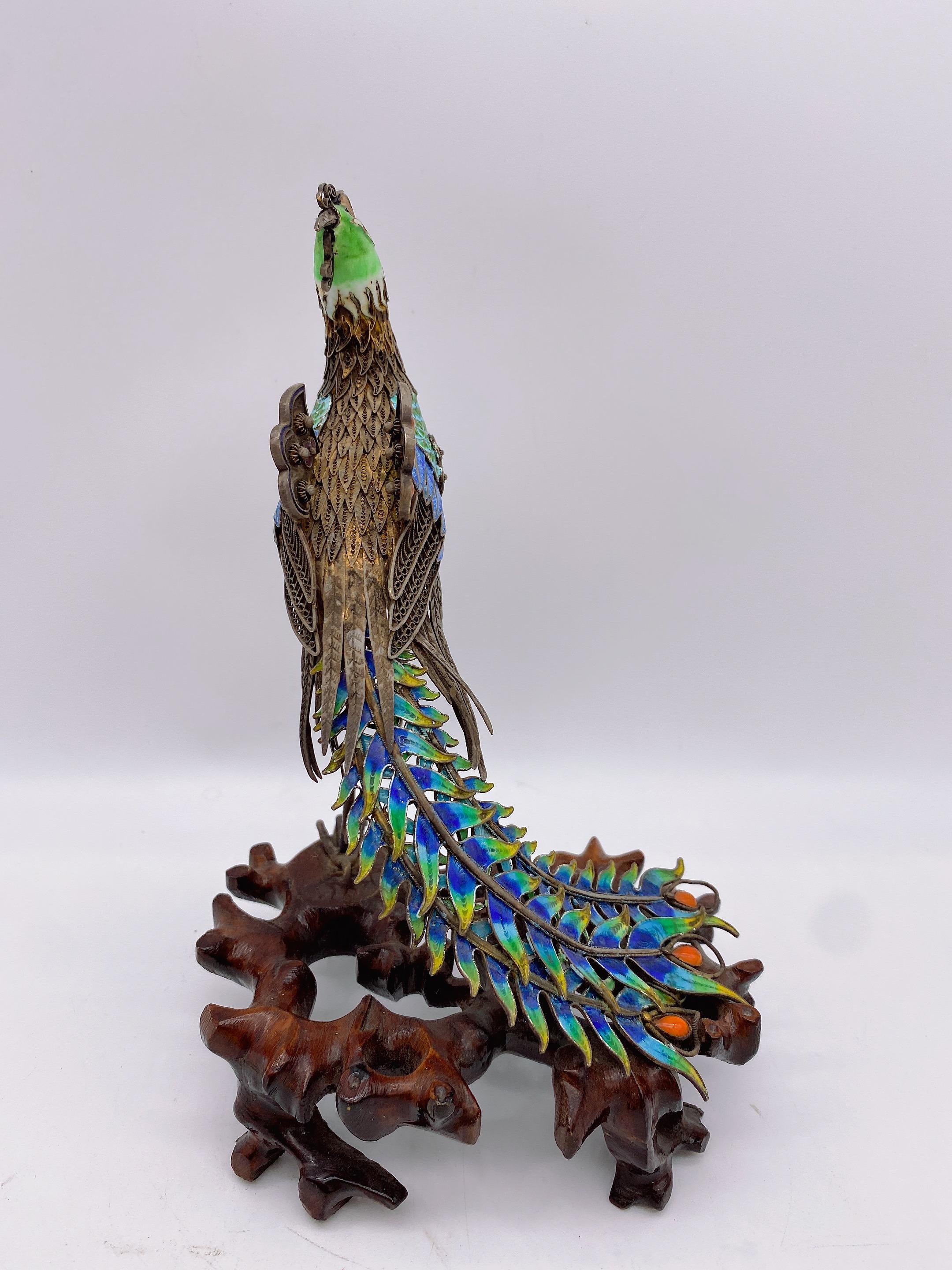 A antique unique incredible Chinese gilt sterling silver cloisonne phoenix on wood base, statue features beautiful emamel in blues, greens with jewels , some toning to the silver but otherwise fantastic condition, cloisonne is in beautiful shape.