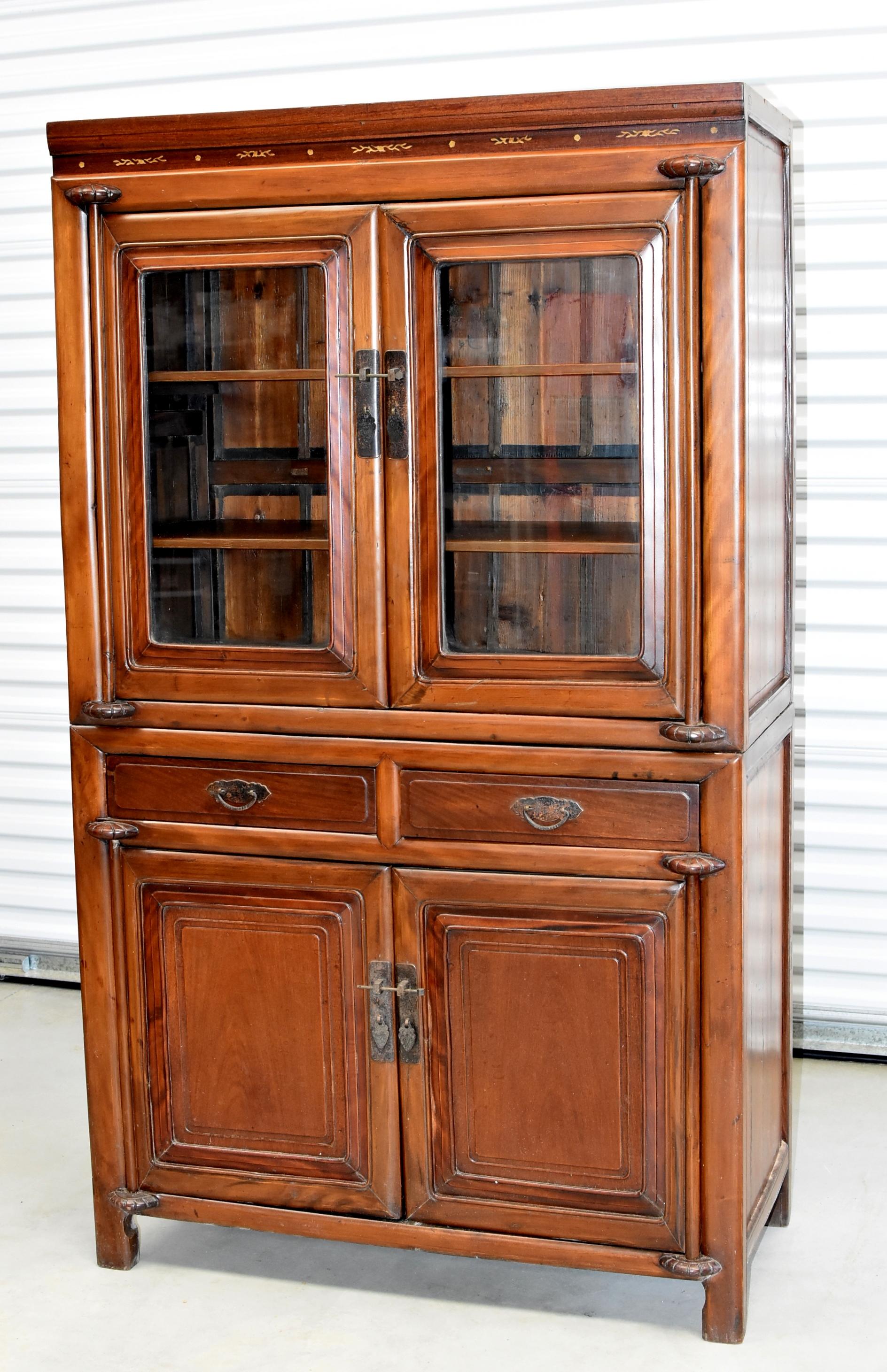 A Ming style solid wood cabinet with glass doors and removable shelves from the Ning Bo vernacular culture. Solid single panels make the door and drawer fronts. Two full length drawers provide additional storage. Carved thin lines reflect Ming