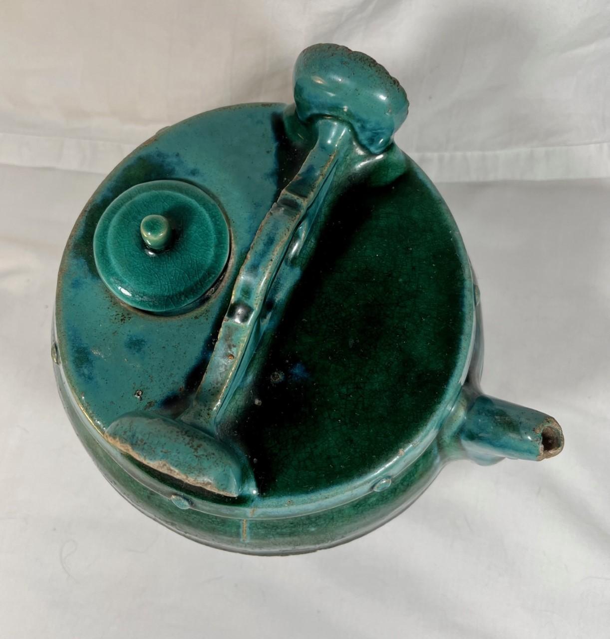 Antique Chinese Green Blue glazed Shiwan pottery teapot dates to China’s Kuang Hsu Dynasty and is of the late 19th century. The vibrant teal-green glaze pot features a pouring spout, a carrying or suspension handle and original lid. Teapots such as
