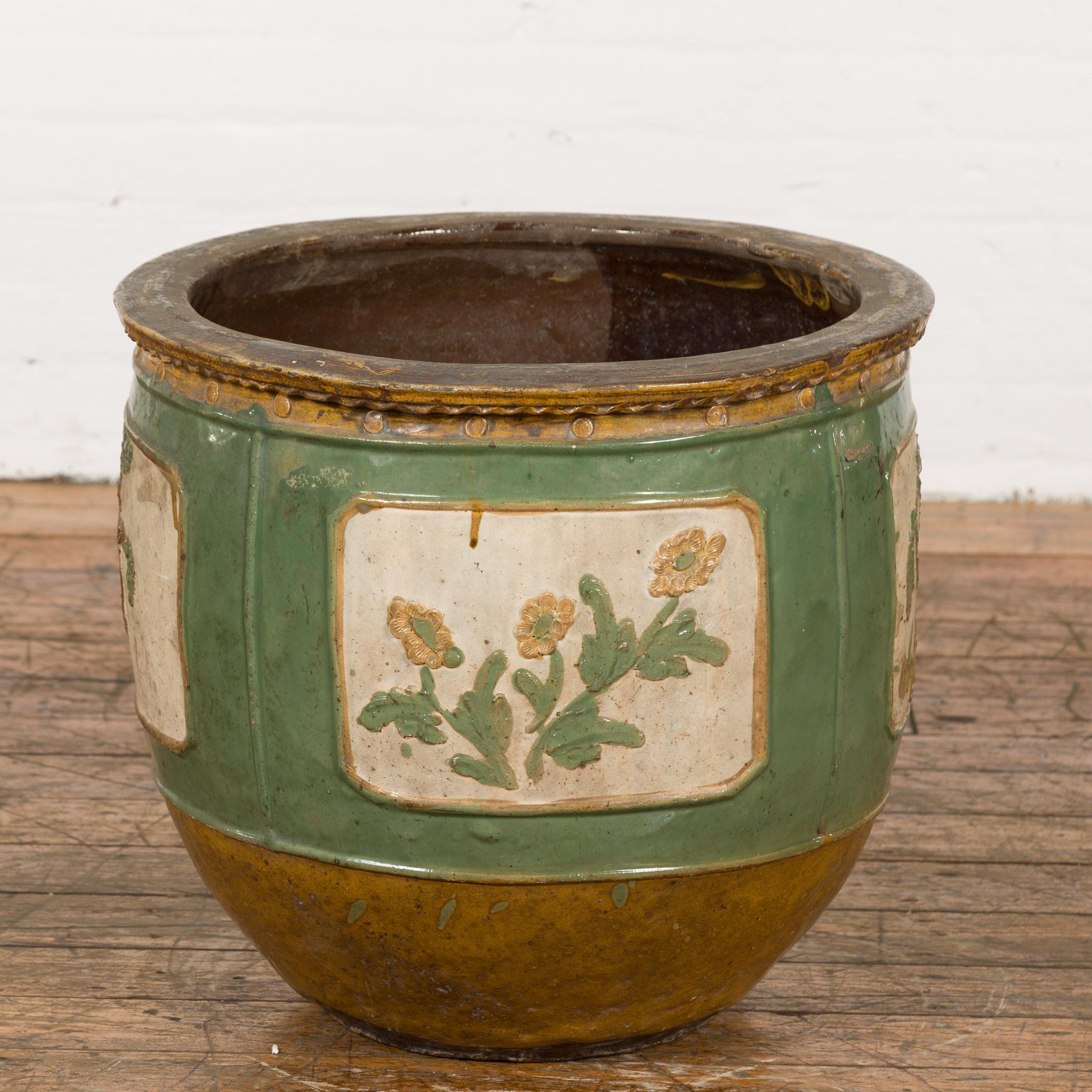 A Chinese planter from the 19th century, with green glazed body, cartouches with flowers and trees and yellow glazed bottom. Created in China during the 19th century, this large planter features a circular opening measuring 15 inches of diameter,