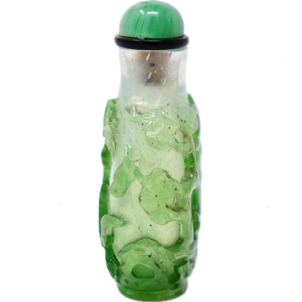A Green-on-Green Overlay Glass Snuff Bottle, Qing Dynasty. A clear bubbly  glass bottle of flattened teardrop form with a cylindrical neck, and  a neatly carved oval foot rim. The transparent glass overlaid in a pale-green translucent green glass