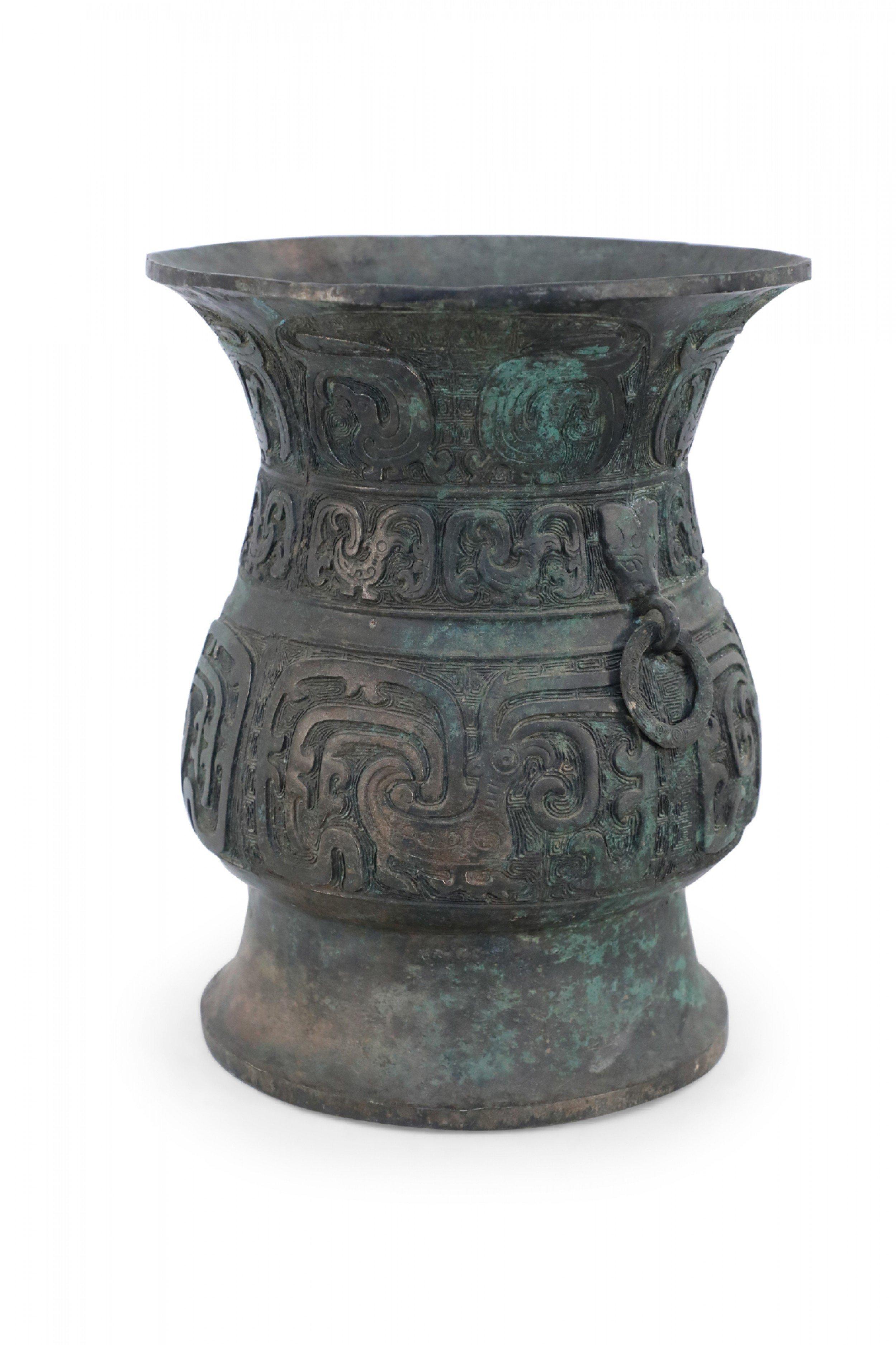 Antica urna rituale cinese in bronzo verdeggiante in stile Dinastia Han con motivi arcaici in rilievo che ne avvolgono la forma e sono accentuati da piccoli anelli su due lati sotto l'apertura. Caratteri impressi sulla base.

Condit: Buono; Usura