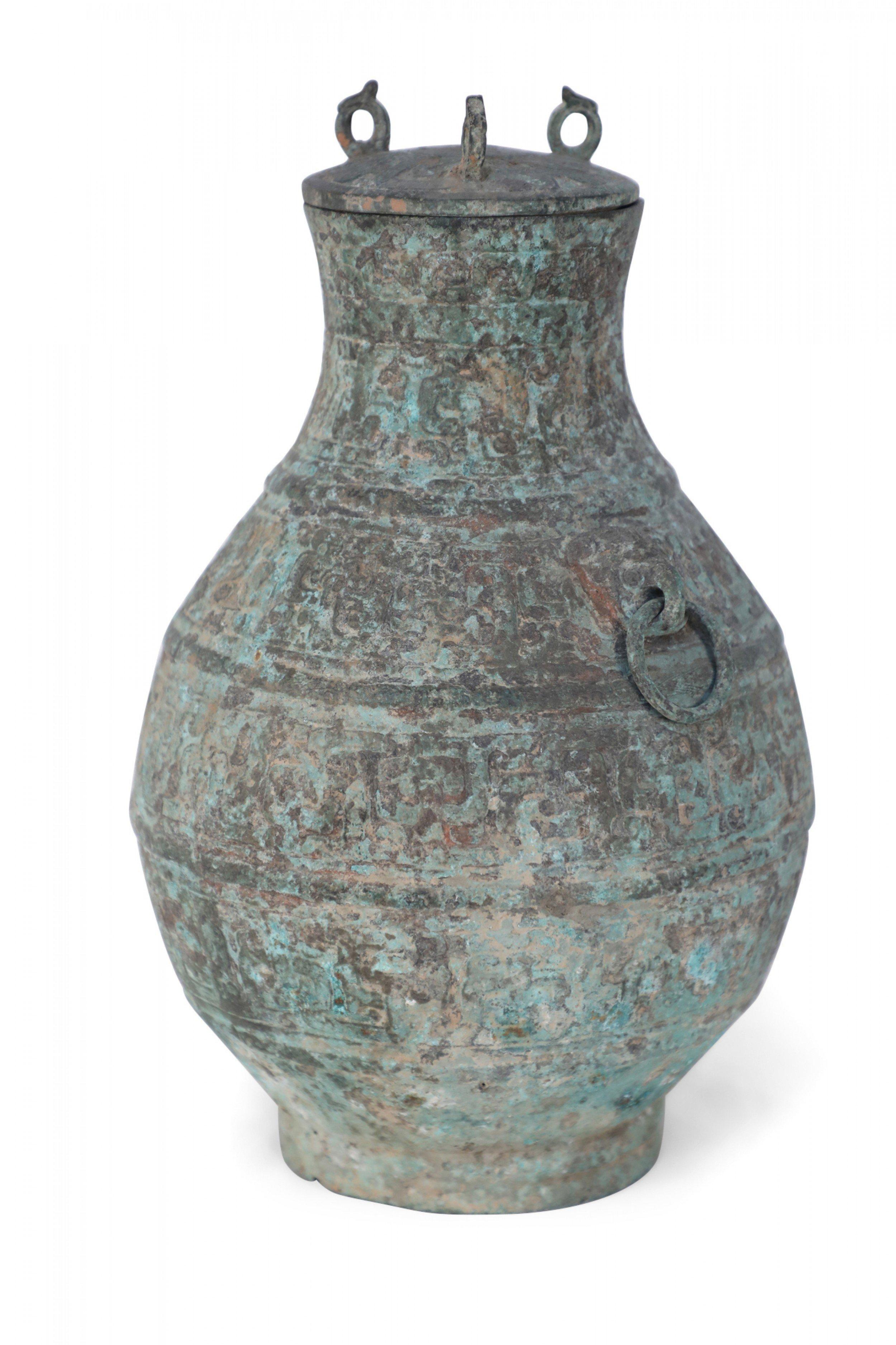 Antique Chinese Han Dynasty-style verdigis bronze ritual wine vessel with raised archaistic patterns, accented with two rings and topped with a lid bearing three bird-form finials.