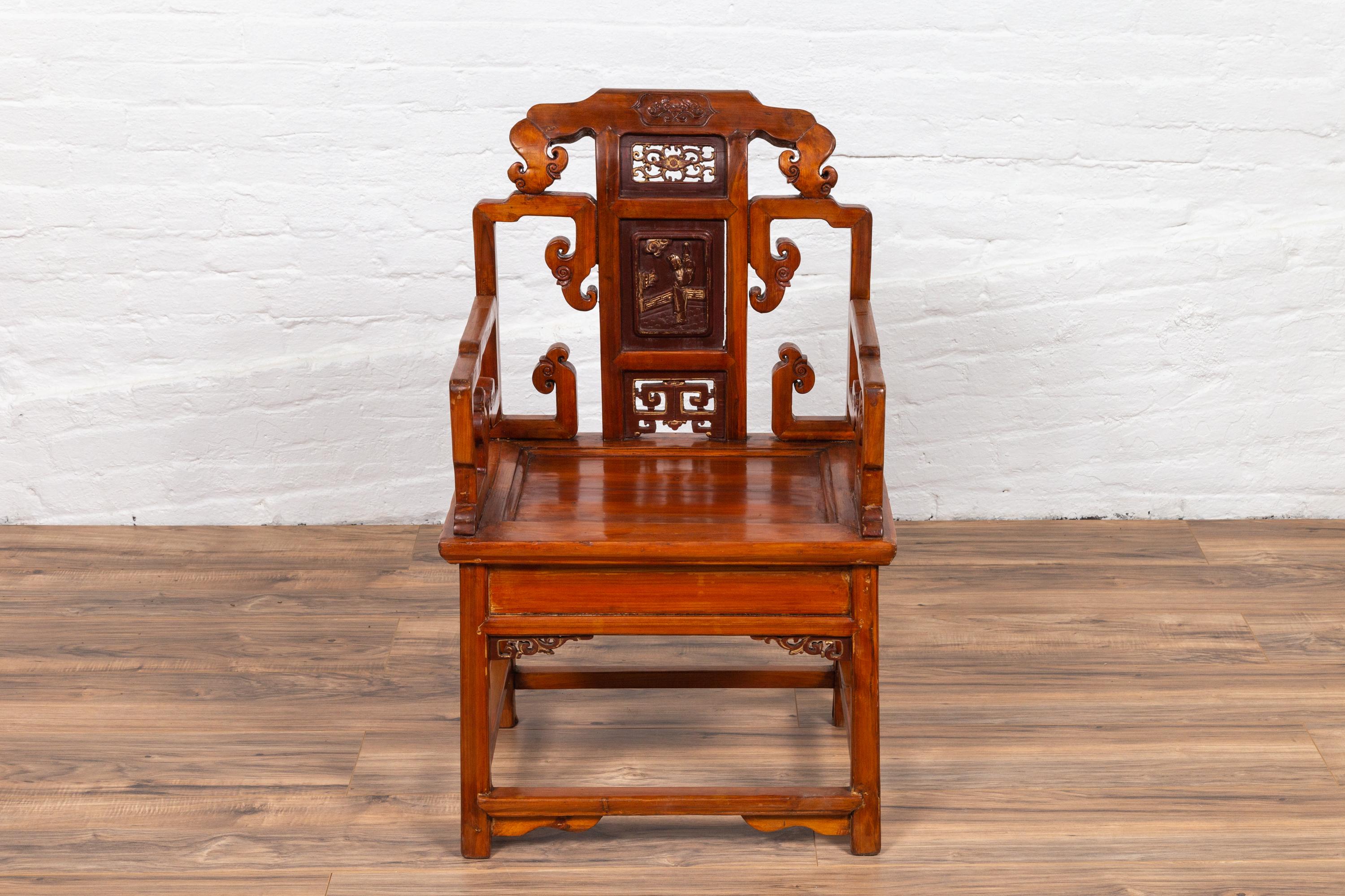An antique Chinese wooden chair from the 19th century, with hand carved panels, red and gold accents and natural wood patina. This Chinese chair captures our attention with its exquisite silhouette and intricate carving. Our eye is immediately drawn