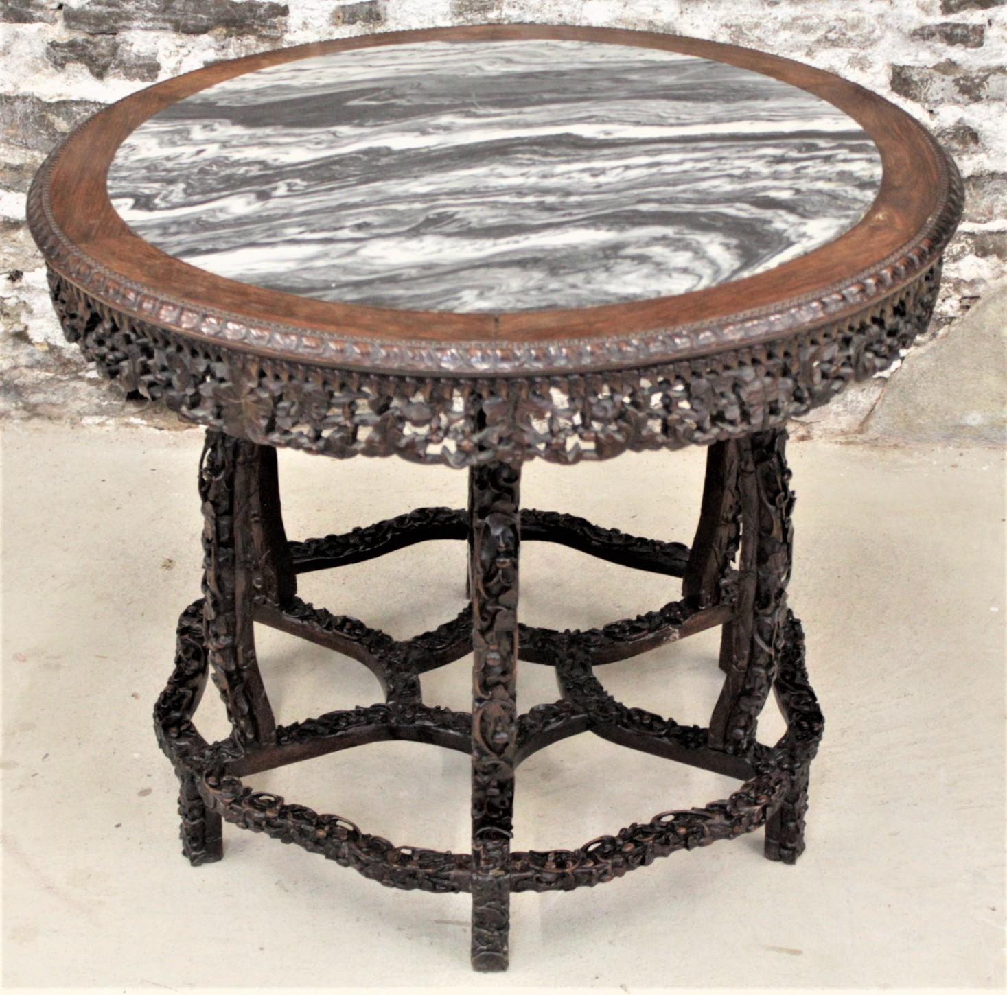 This antique hand-carved hardwood center table is unsigned, but presumed to have originated in China in approximately 1900 in the period Chinese Export style. The table has a round top with an inset piece of polished dream stone. The top has