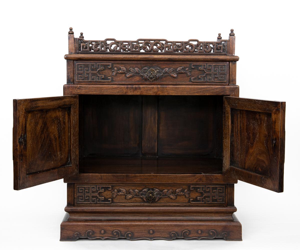 This finely carved Chinese antique hand carved tabletop small cabinet features dragons and featuring two opening doors, two drawers and a gallery top. It carved on the front and two sides.