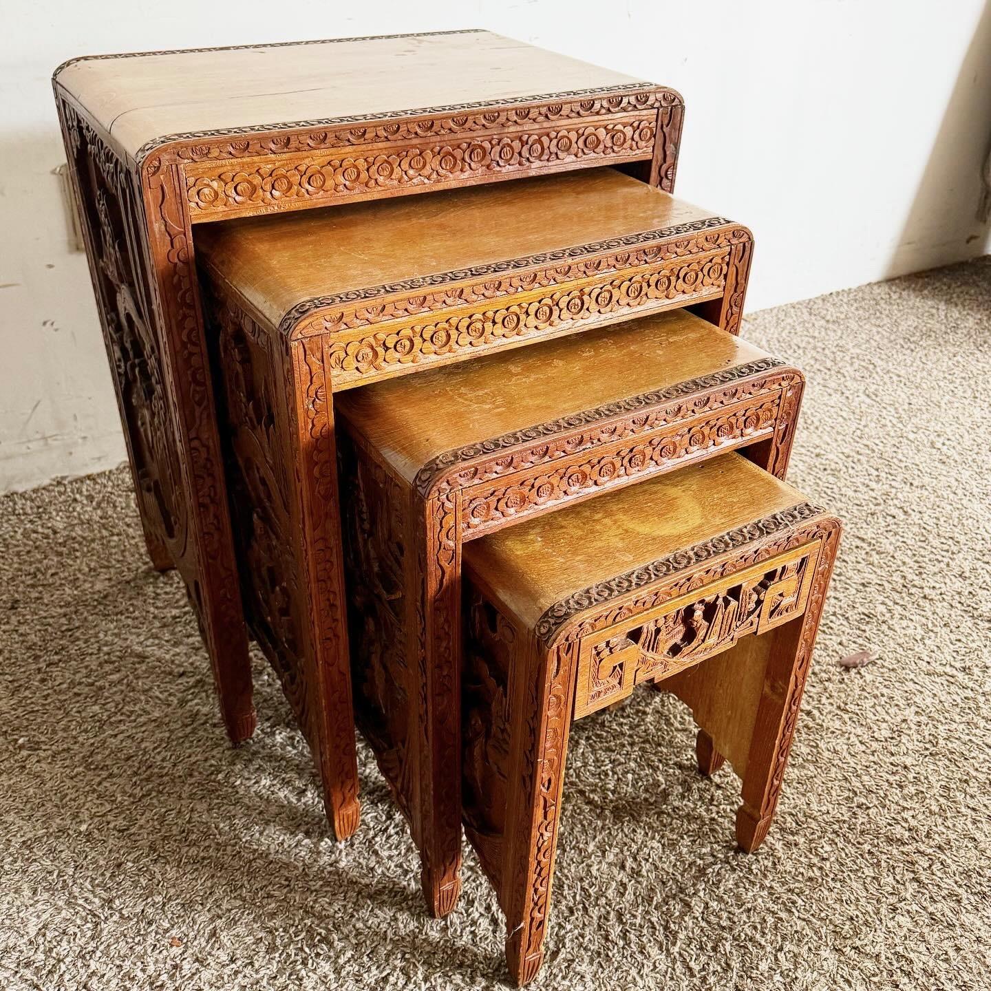 This exquisite set of four Antique Chinese Hand Carved Nesting Tables is a masterpiece of craftsmanship and traditional design. Each table in the set features intricate carvings with detailed Chinese depictions on the sides and borders, showcasing