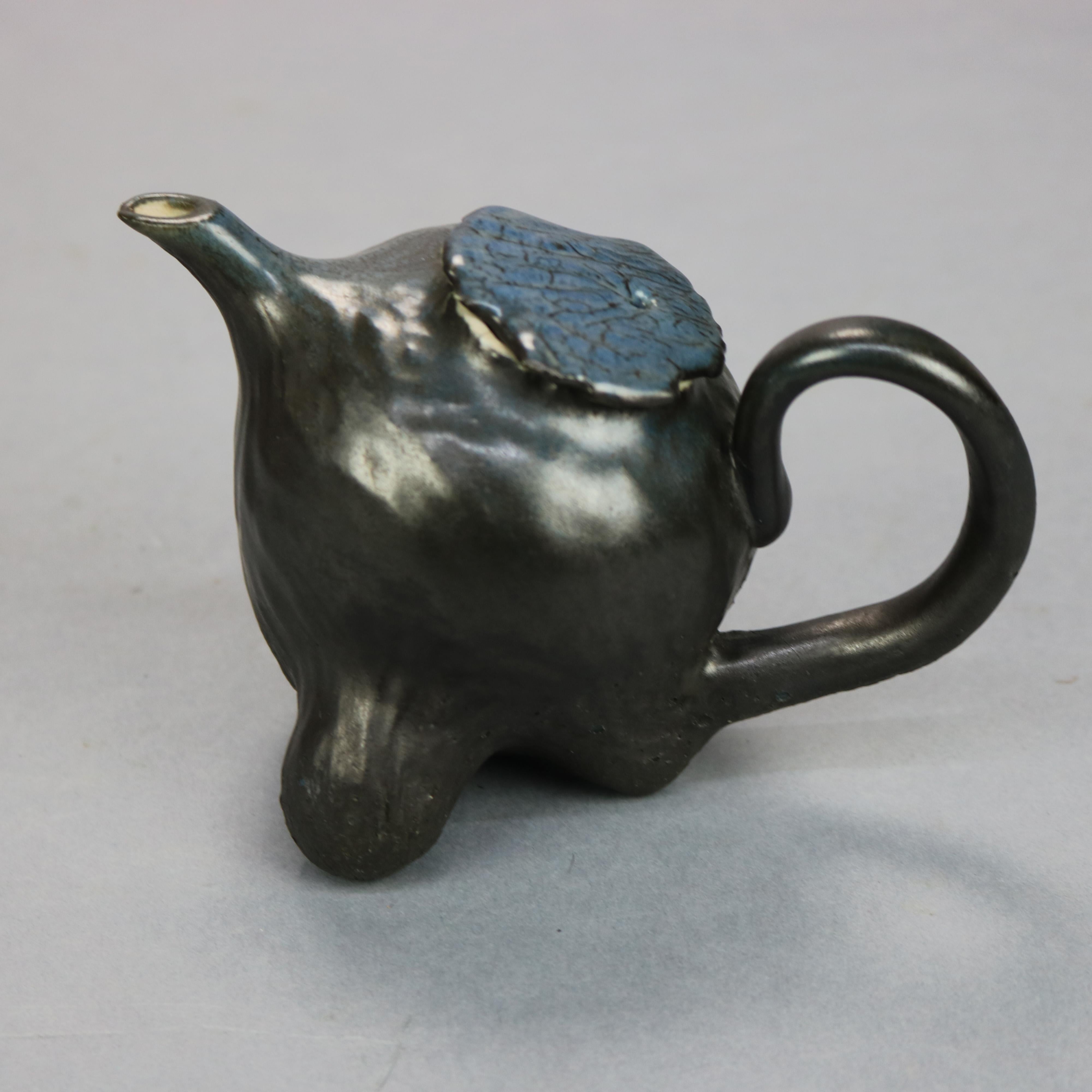 An antique Chinese oriental hand crafted teapot offers hand thrown and glazed pottery lidded teapot seated on carved hardwood base in root form, c1890

Measures: 4.25