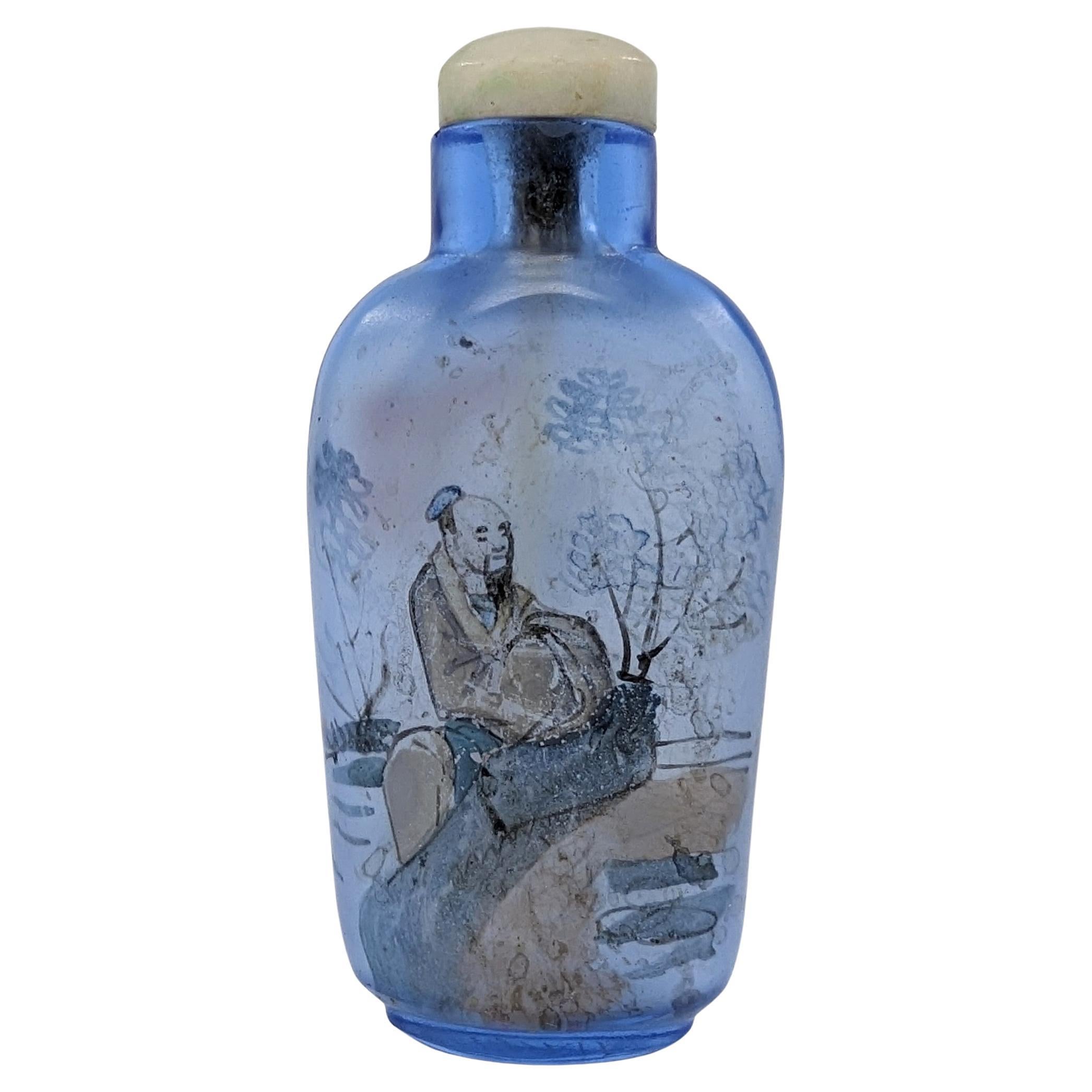 An antique Chinese inside painted blue glass snuff bottle with a jadeite stopper. Inside painted with a sitting scholar to one side and a pacing scholar to the other side

Late 19th to early 20th Century, Late Qing to Republic period
