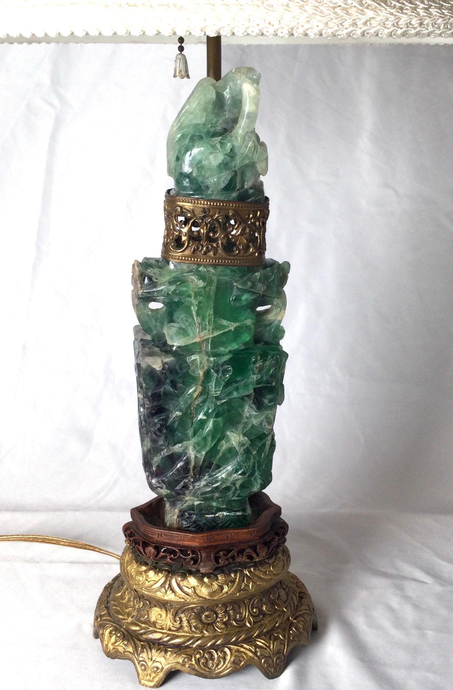 An antique Chinese carved green quartz vessel now as a lamp. The vessel from the 19th century lamped in the early part of the 20th century. Gilt base with pierced brass band at the neck. The quarts with natural lines and infractions which are normal