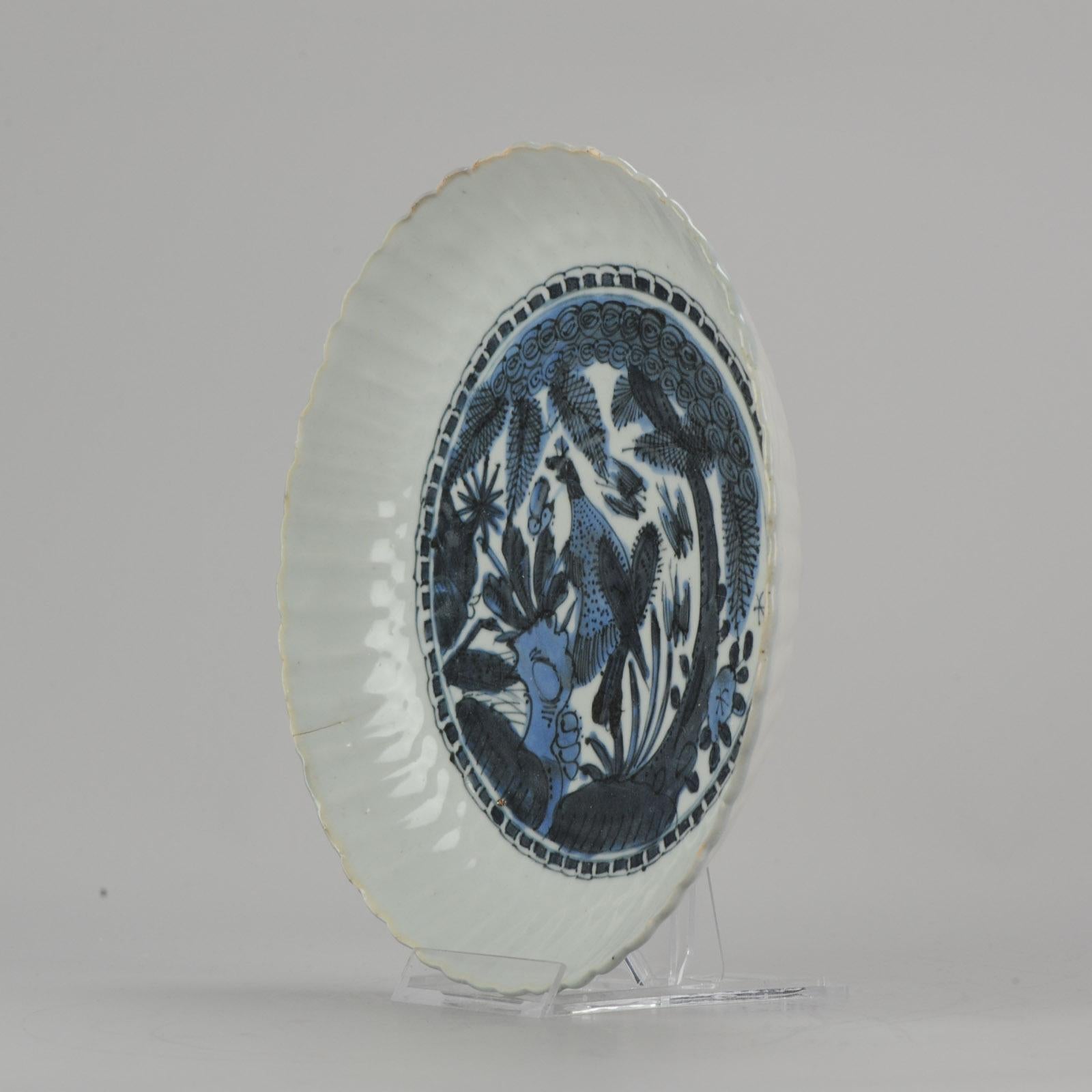 A very nicely decorated kraak plate. Dish on footring, spreading sides, lobed rim. Kraak porcelain, decorated in underglaze blue with a bird of prey perched on a rock near a flowering plant. Above and besides a pine tree. Three birds flying over the