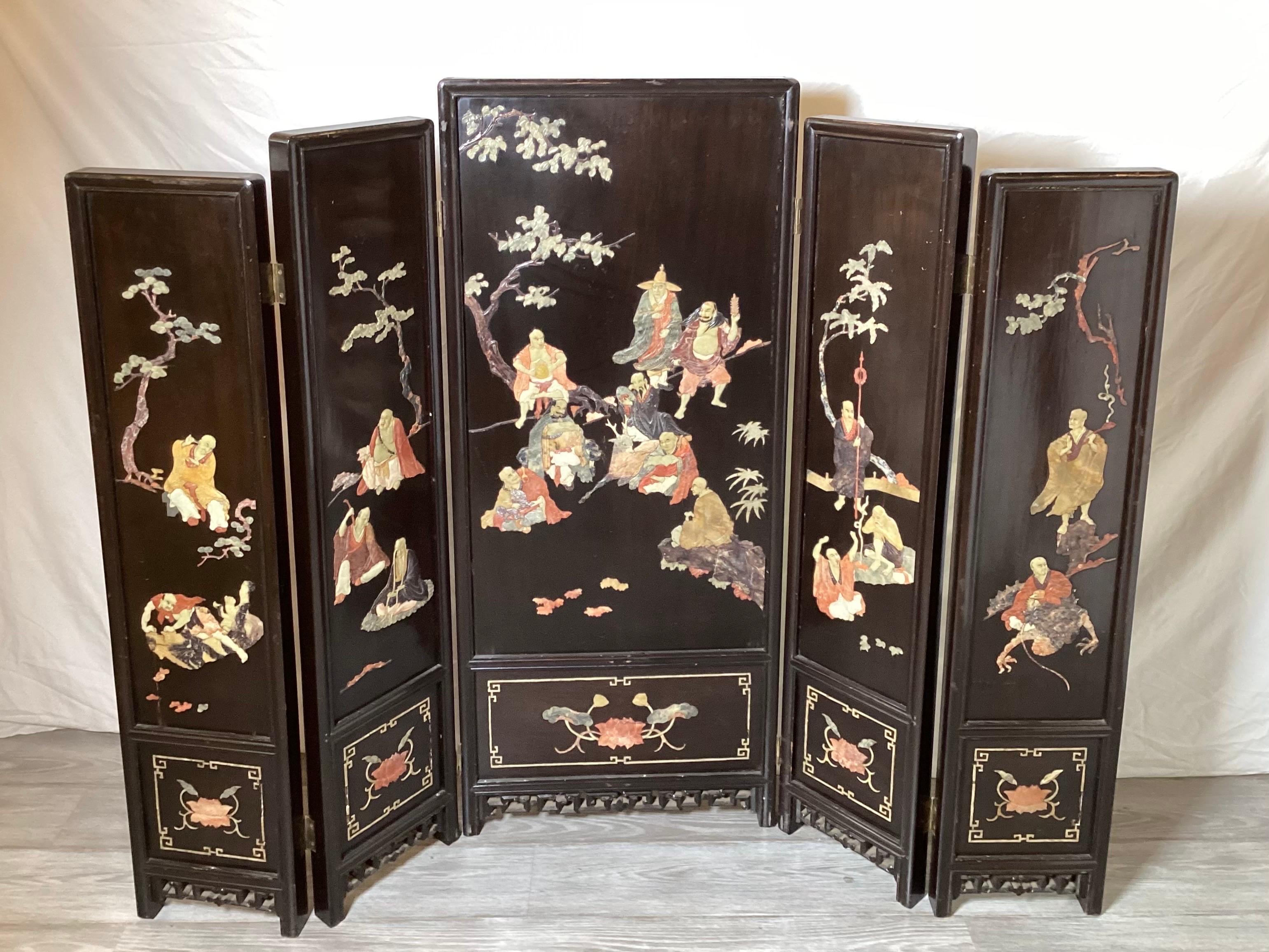 A late 19th century five panel screen with black lacquer finish. Each panel with carved soapstone figures of immortals. The center panel is 19.5 inches wide, the side four panels are 9.5 each, total expansion is.