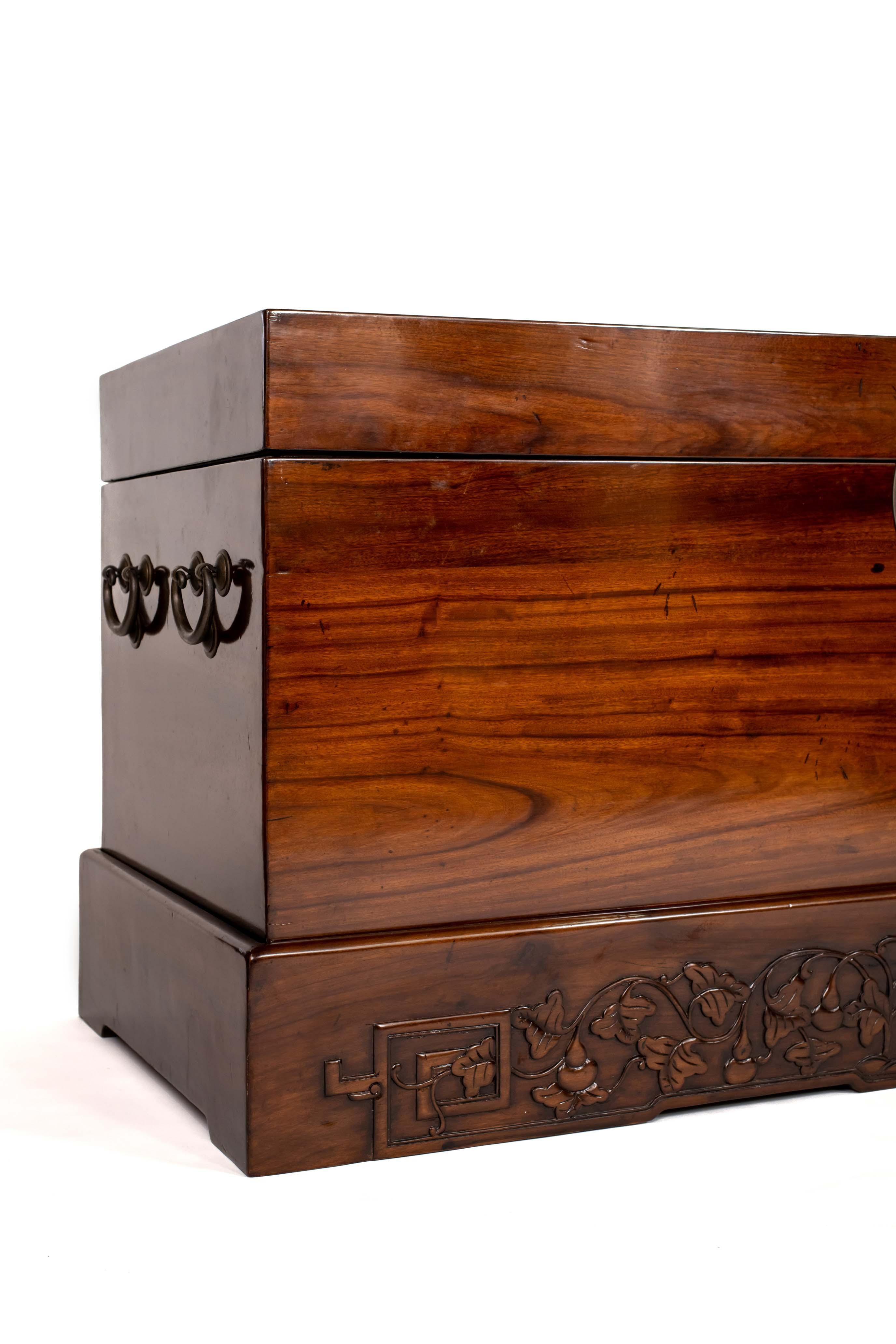 Of rectangular form, the chest with wood of smoothly-grained texture, warn tone and attractive patina, round brass lock plate set flush, mounted with the front continuing over the lid, the top lid lifting open to an interior with an open storage